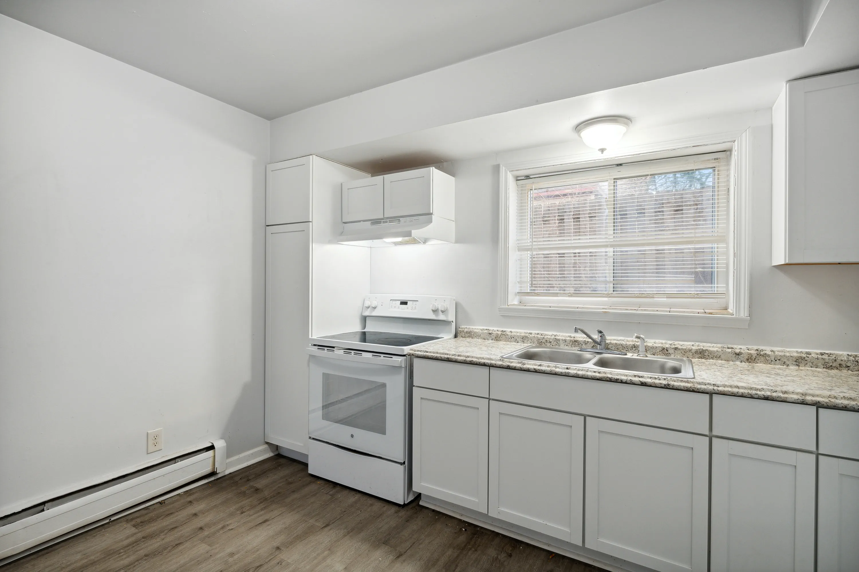 Bright and modern kitchen with sleek white cabinets, stainless steel appliances, and large windows offering ample natural light.