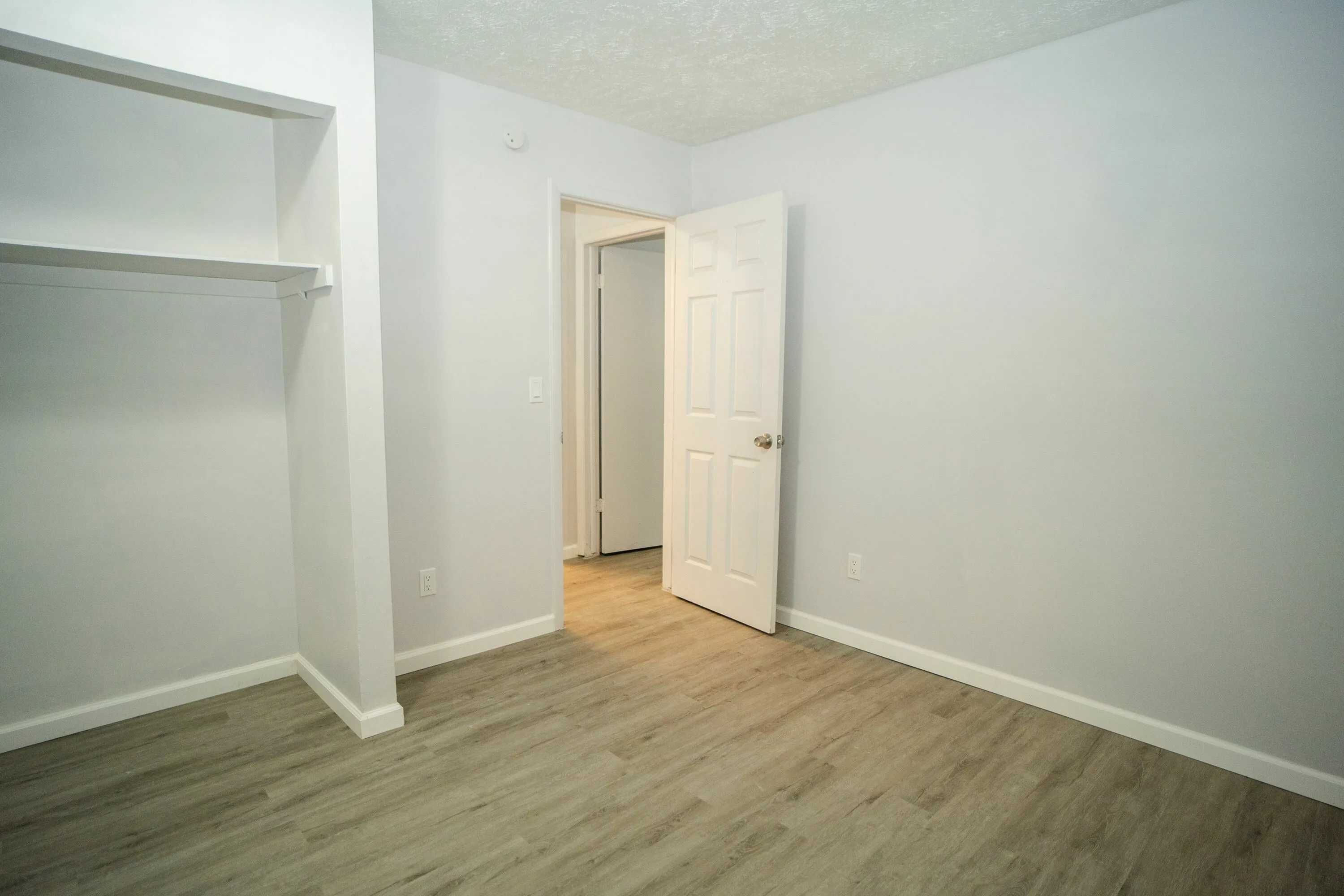 Bright, spacious room with elegant hardwood floors, open shelving, and a neutral color palette, perfect for customization.