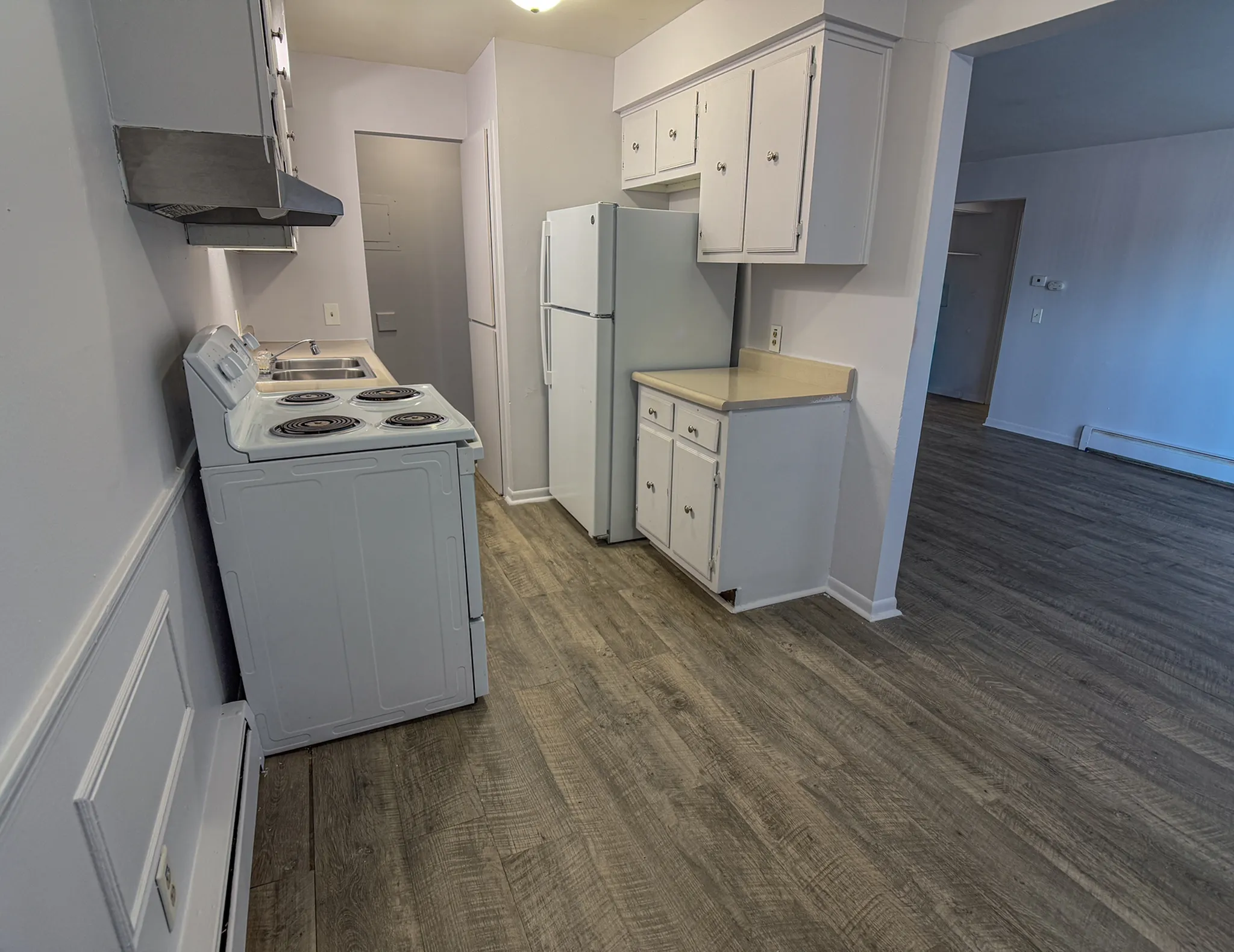Modern kitchen featuring sleek white cabinets, spacious countertops, and stylish flooring leading into an open living area.