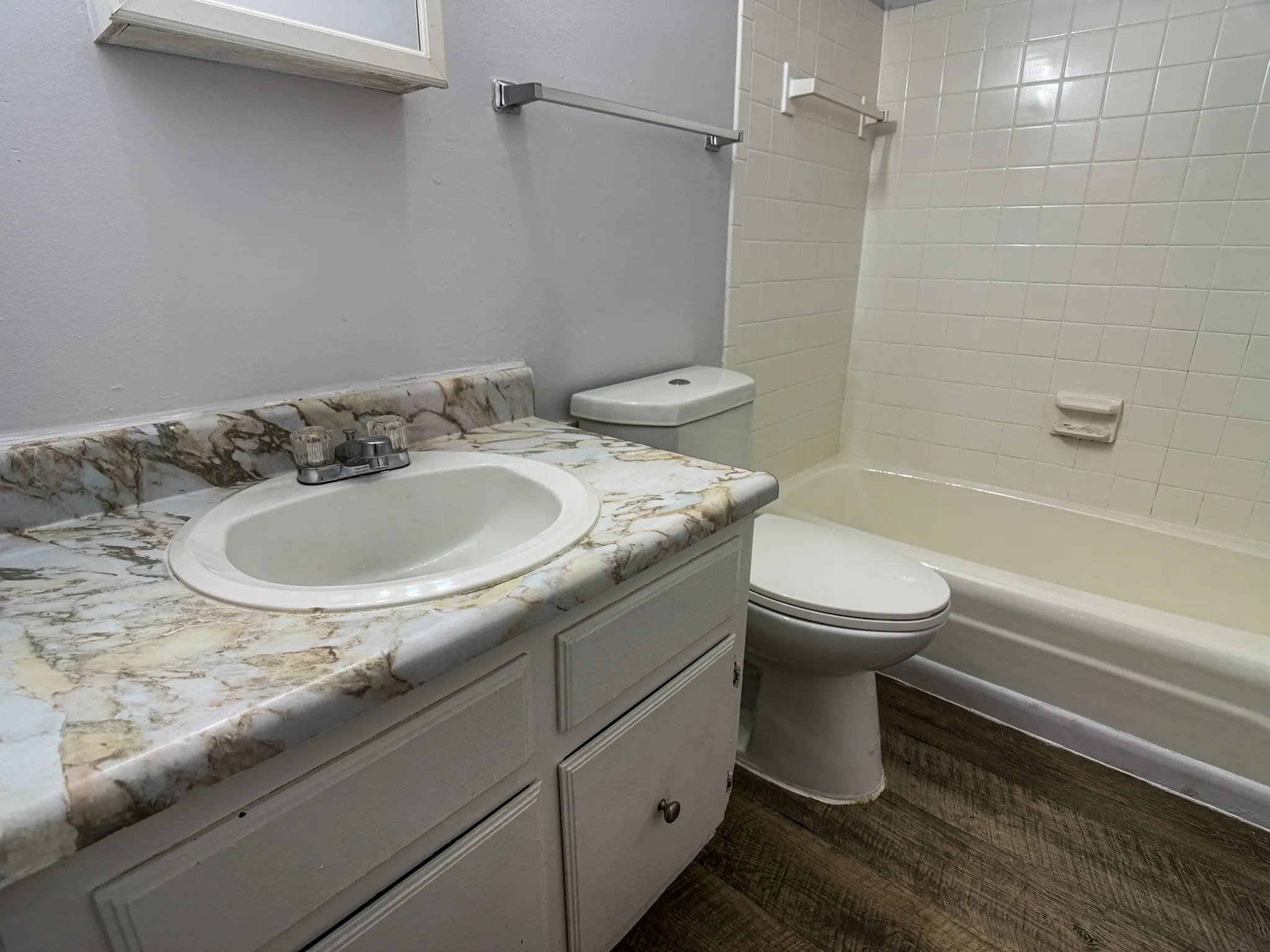 Chic bathroom featuring a marble countertop sink, modern fixtures, and elegant tiled bathtub, creating a stylish and inviting space.