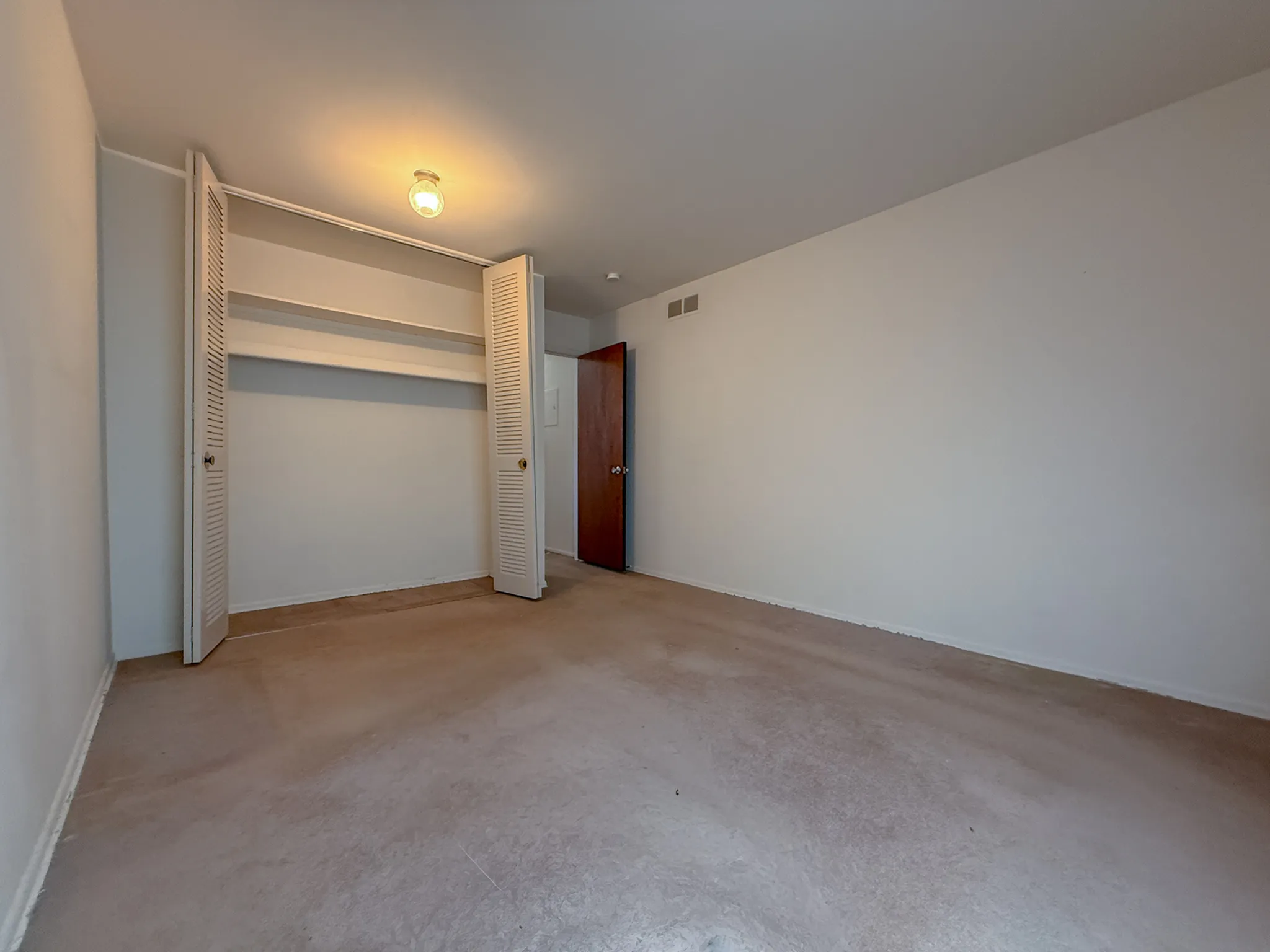 Spacious, well-lit bedroom with open closet and neutral carpet, perfect for personalization.