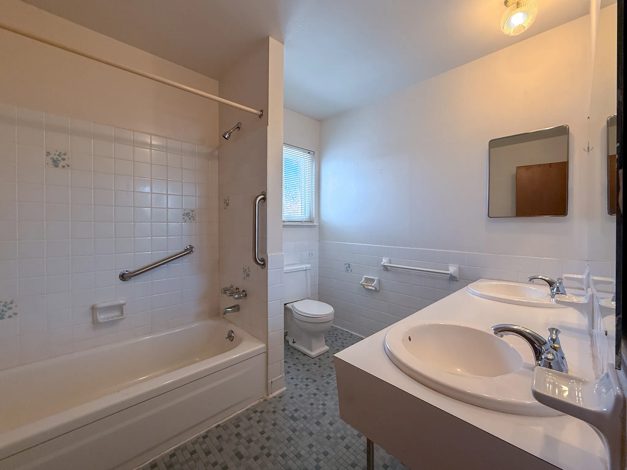 Bright and spacious bathroom featuring a double vanity, modern fixtures, and a tiled shower-tub combo.