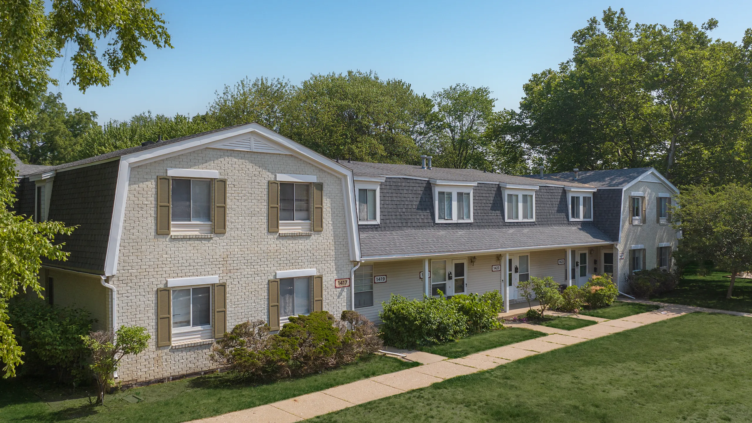 Charming townhouse complex with fresh landscaping, featuring classic exterior design and beautiful greenery for a serene suburban feel.