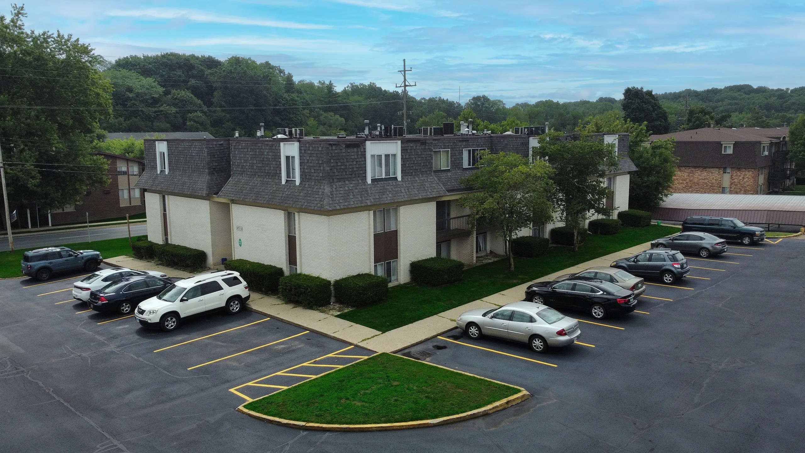 Charming apartment building with ample parking, nestled in a lush, green neighborhood.