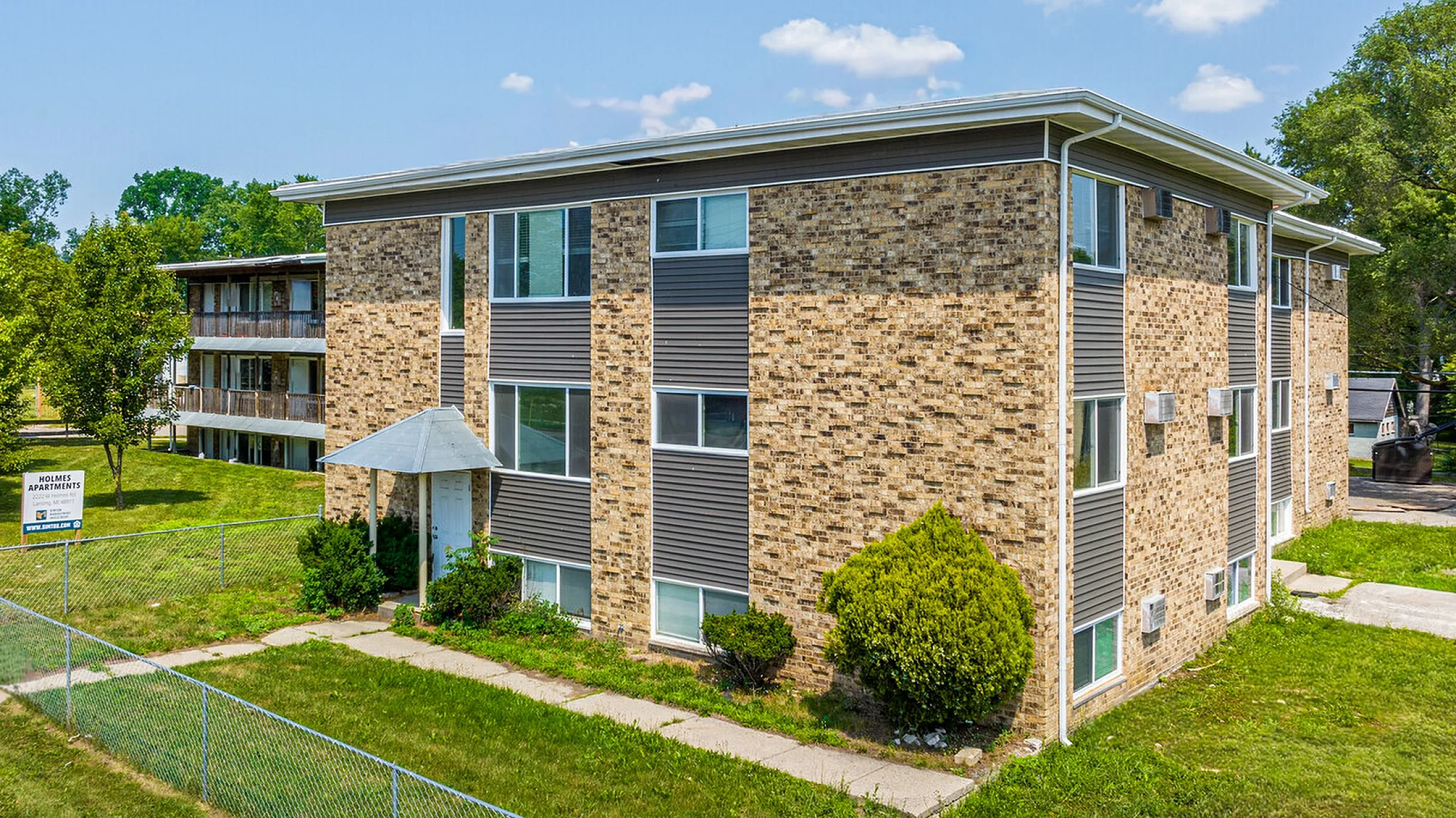 Charming brick apartment building with modern design and lush greenery, offering a serene living environment.