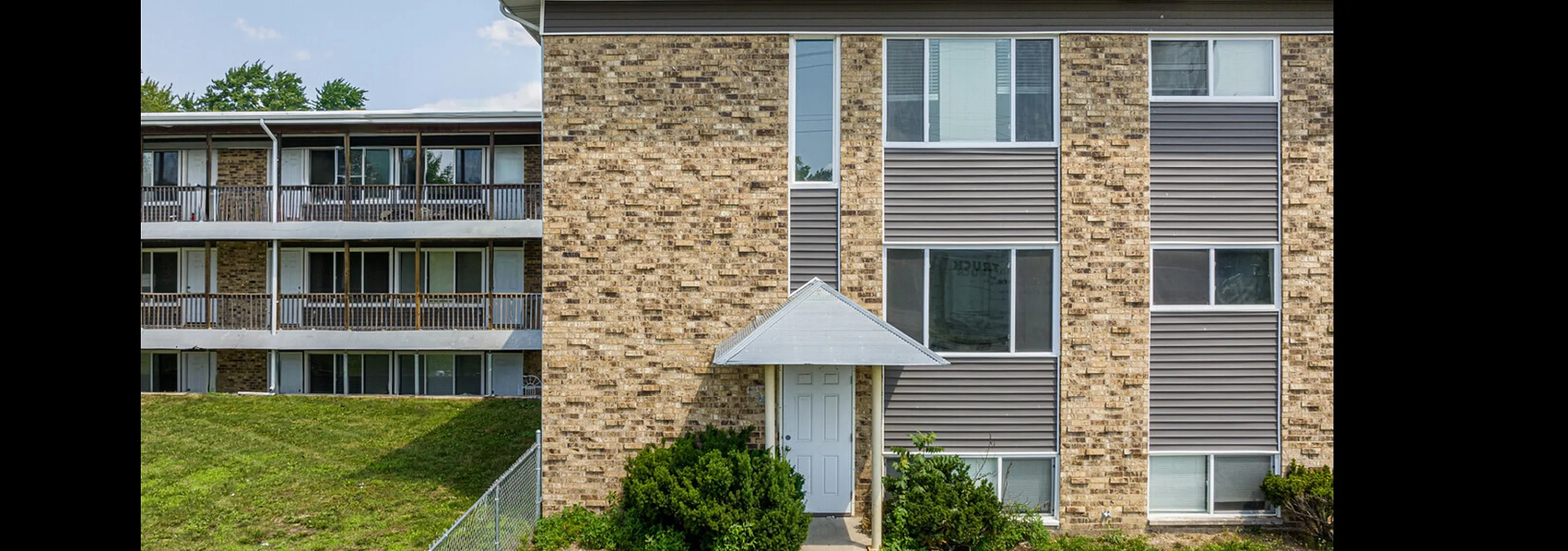 Charming brick apartment building with modern features, lush green surroundings, and large windows for ample natural light.