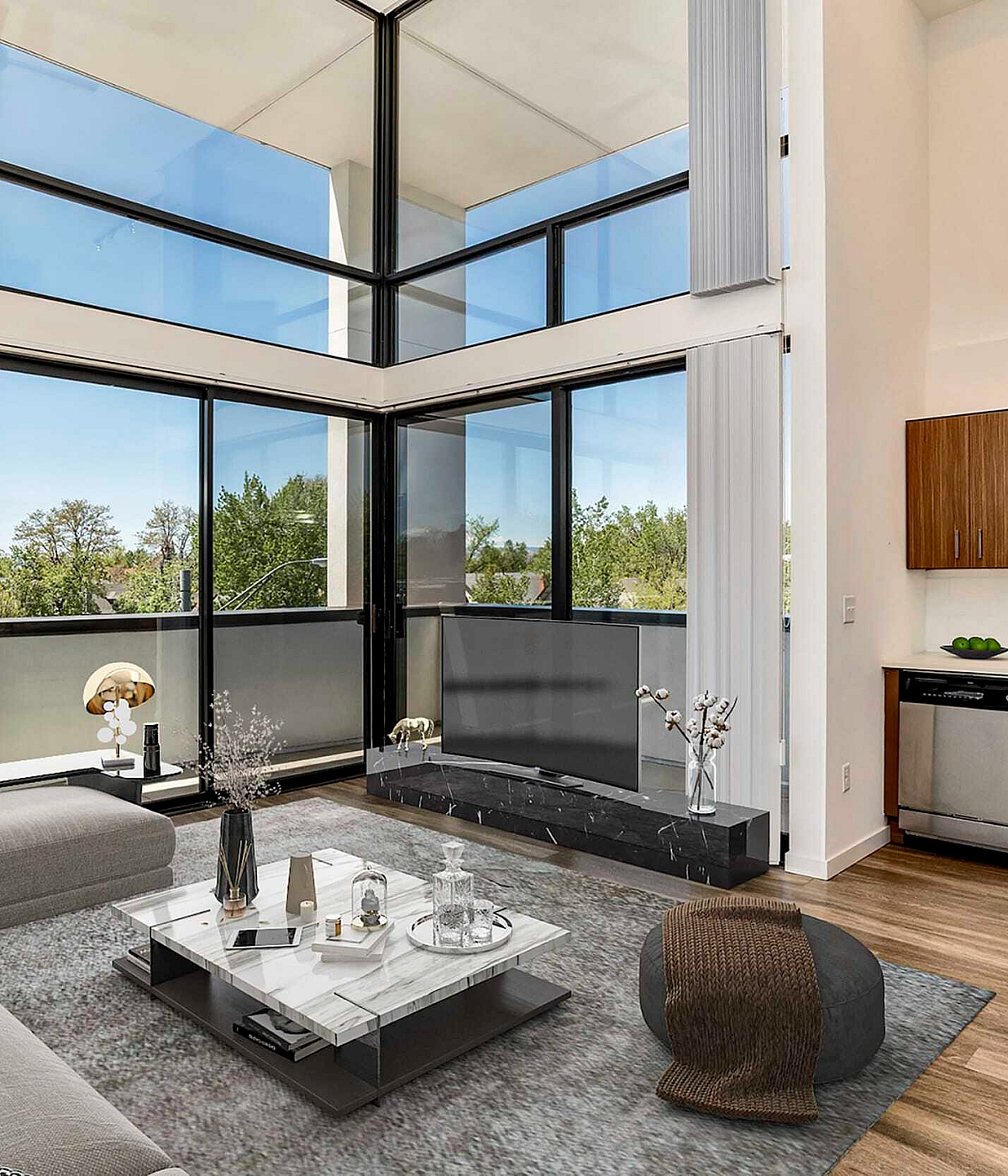Modern living room with expansive floor-to-ceiling windows, elegant sectional sofa, and a stylish open kitchen with sleek wood cabinetry.