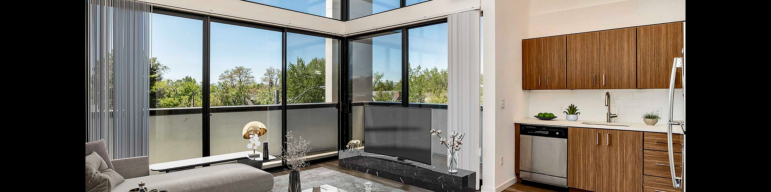 Stunning open-concept living room with floor-to-ceiling windows and modern kitchen cabinetry, offering abundant natural light and stylish design.