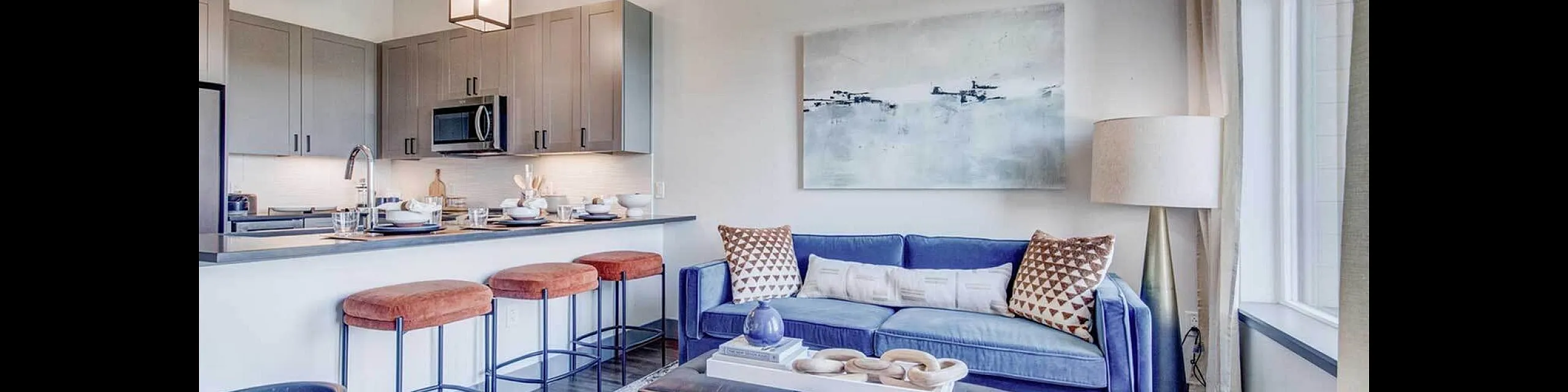 Chic open-concept living room and kitchen featuring stylish decor, modern lighting, and cozy seating, perfect for entertaining.