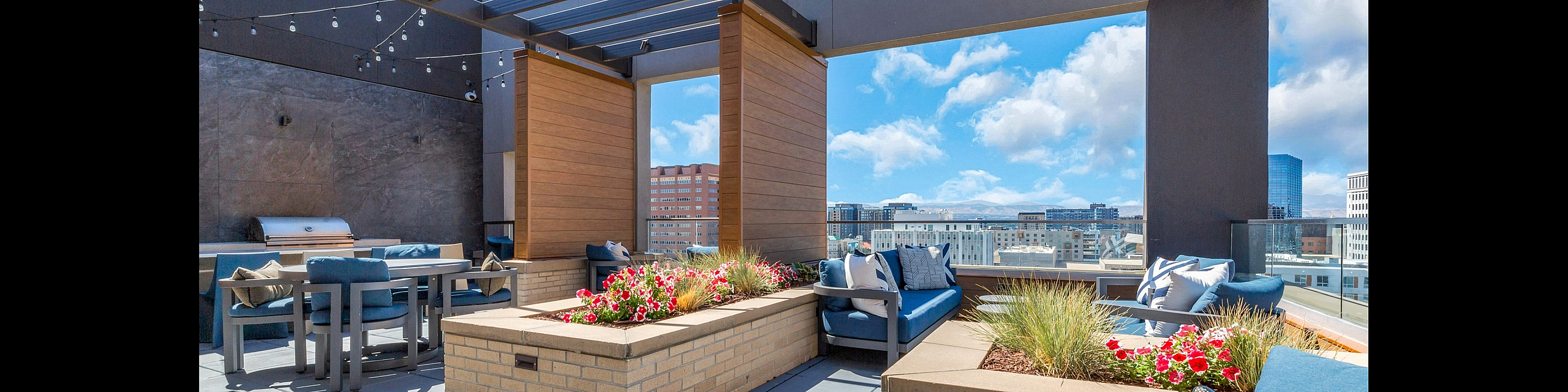 Elegant rooftop patio featuring modern outdoor seating, vibrant flower beds, and panoramic city views.