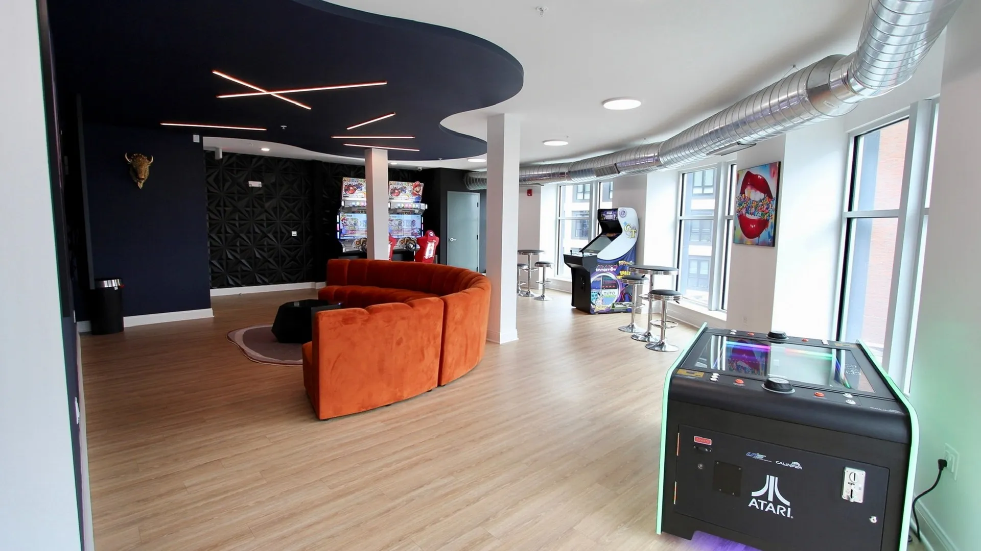 Fun gameroom with wrap-around couch, table games, wall artwork, sitting areas and arcade games.