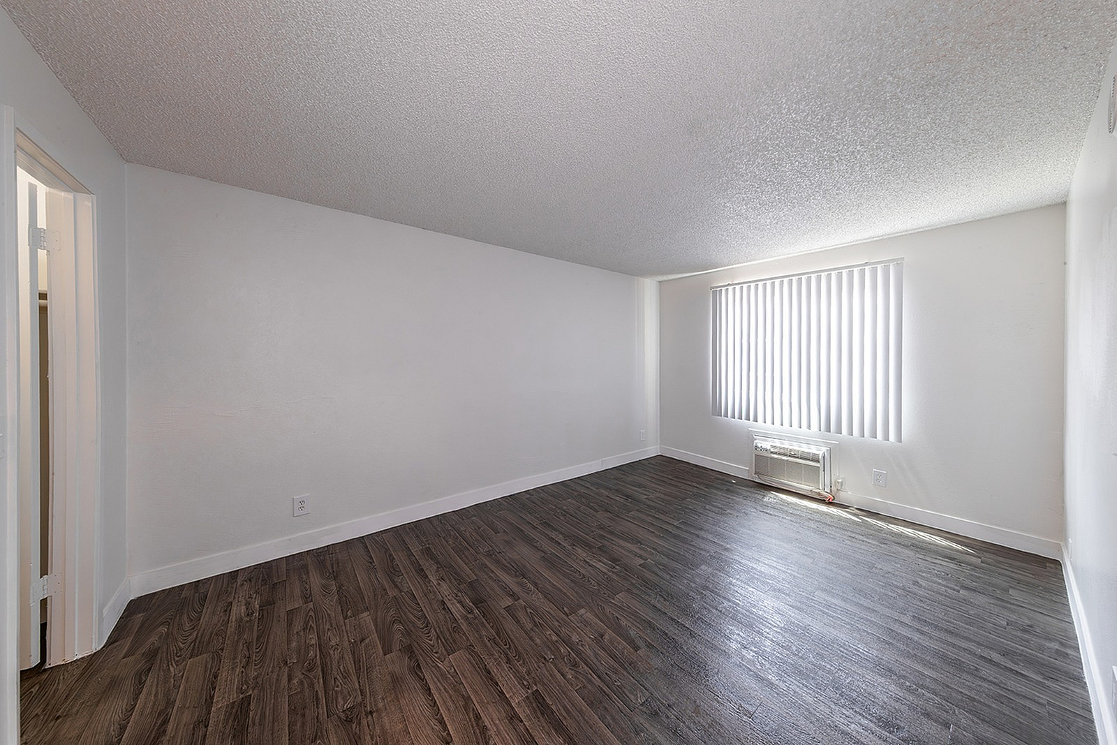 Bright and spacious room with modern hardwood flooring and large window blinds, perfect for versatile styling possibilities.