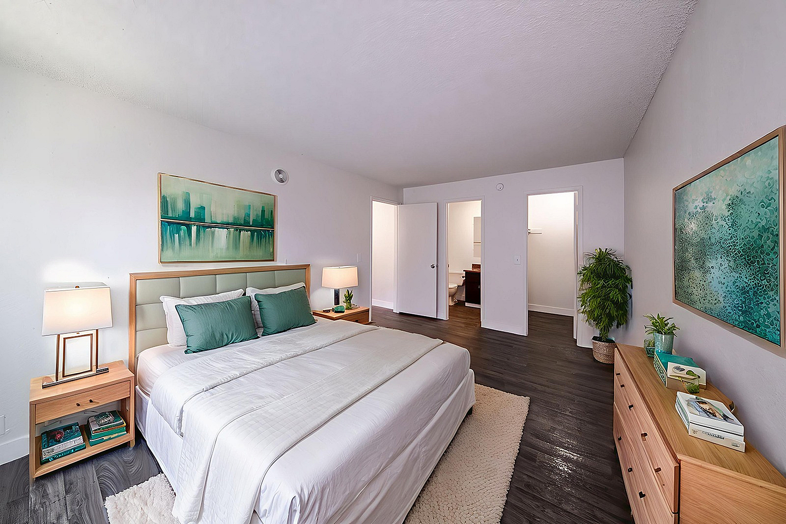 Inviting bedroom with elegant decor, featuring a plush bed, modern nightstands, and vibrant art, surrounded by stylish flooring and soft lighting.