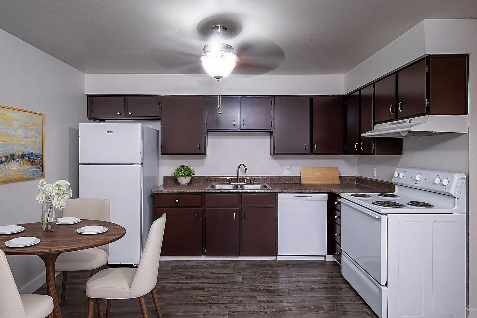 Modern kitchen with sleek dark cabinets, a cozy dining area, and contemporary appliances creating a welcoming atmosphere.