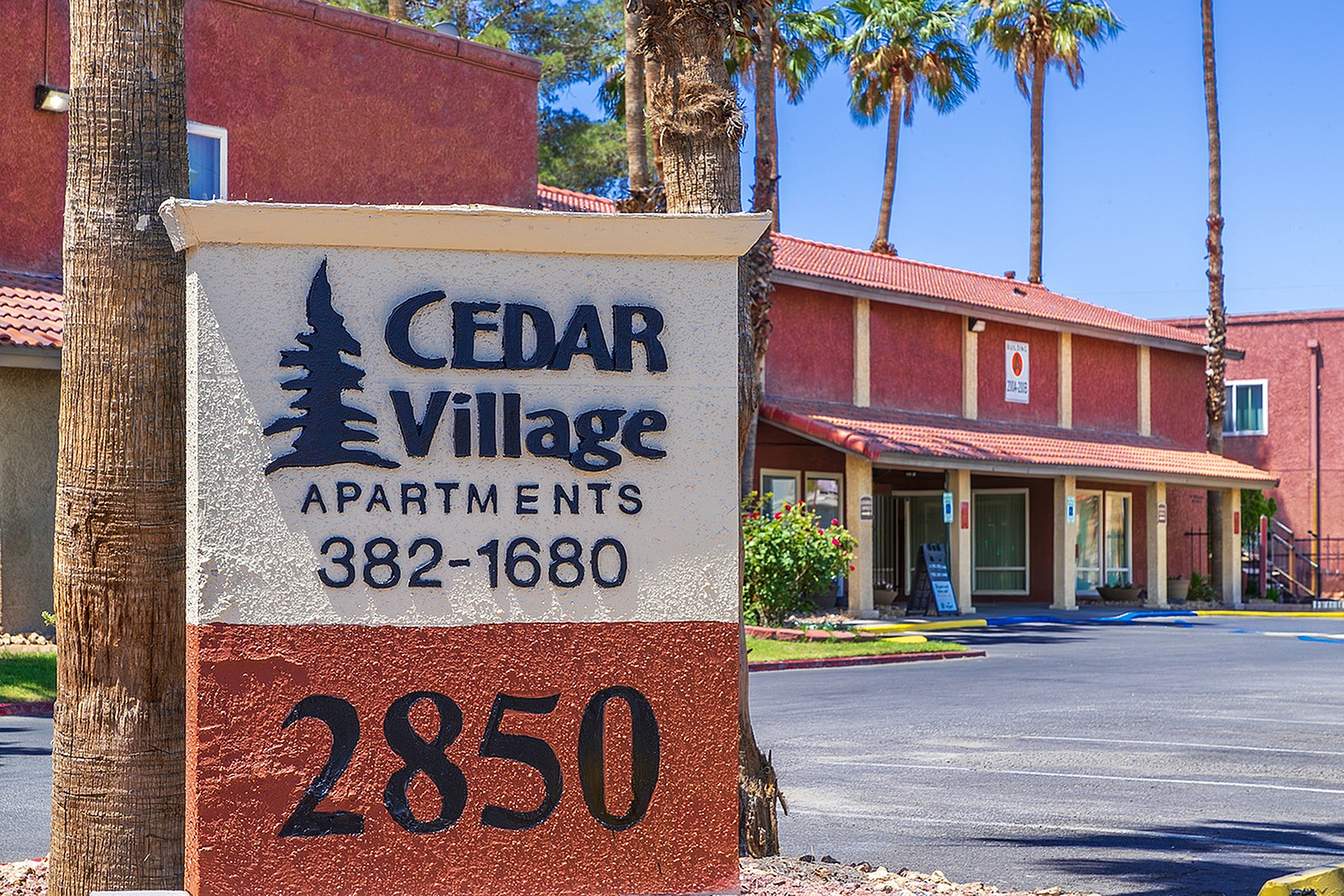 Charming Cedar Village Apartments with desert-inspired architecture, surrounded by palm trees and offering inviting communal spaces.