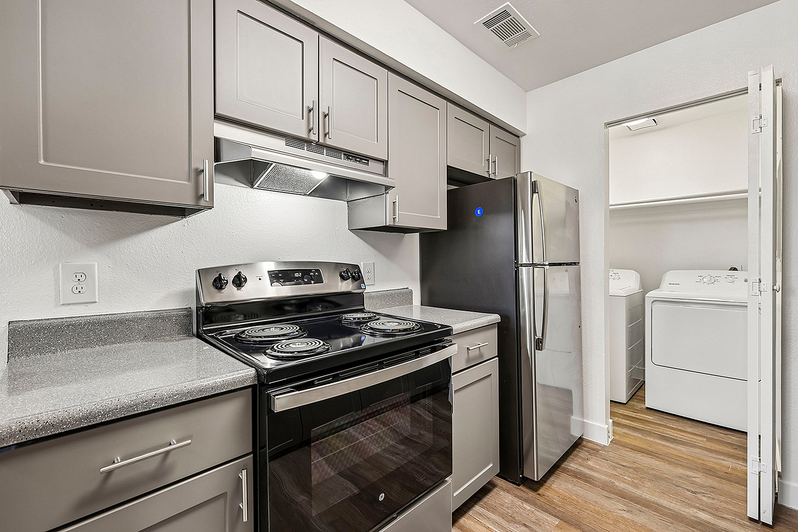 Modern kitchen with sleek stainless steel appliances, elegant cabinetry, and in-unit laundry for convenient living.