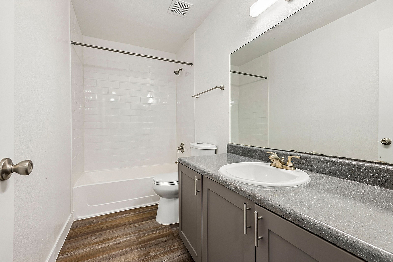 Modern bathroom with sleek design featuring a spacious vanity, polished granite countertop, and elegant fixtures, complemented by a pristine bathtub and contemporary flooring.