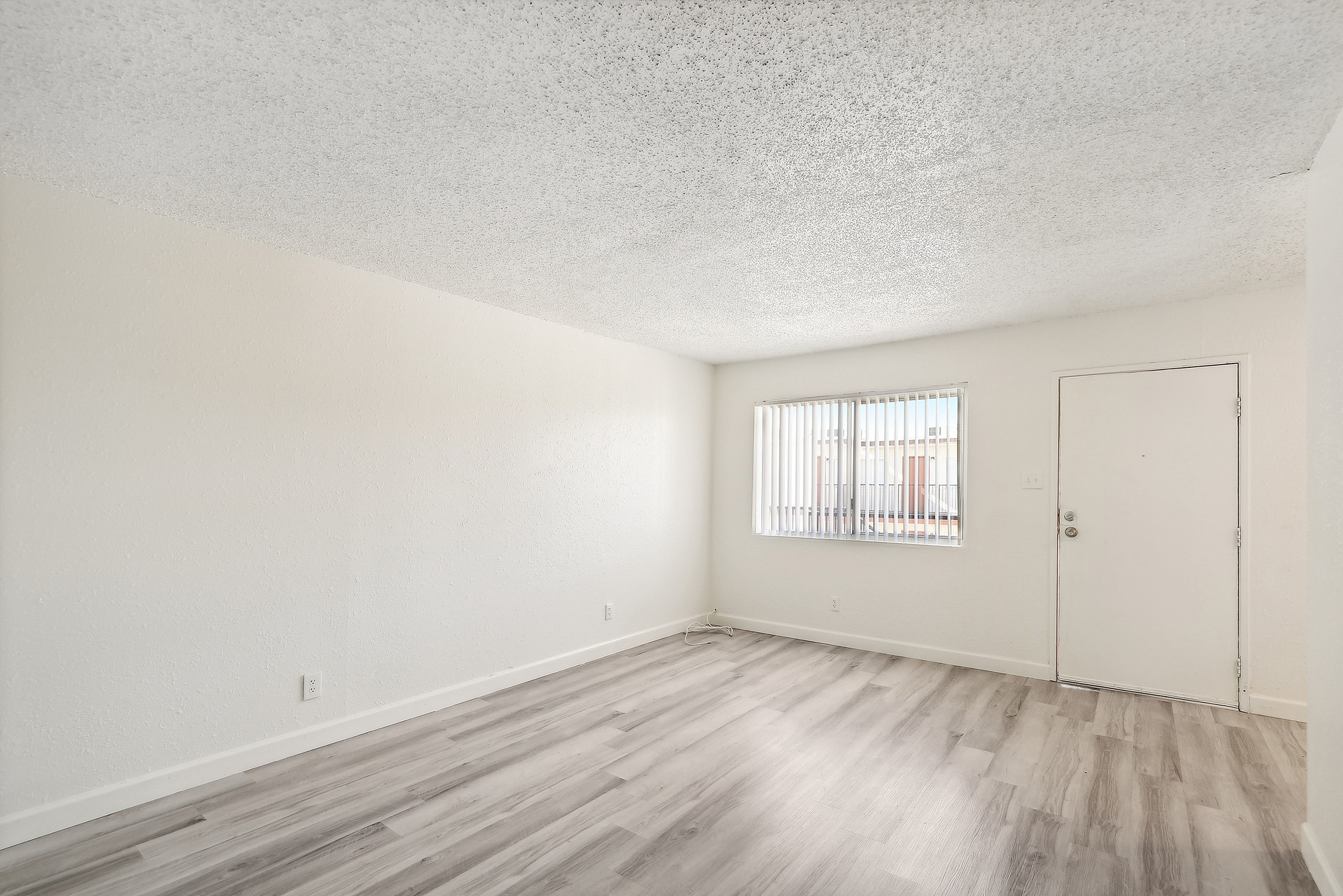 Bright and inviting living space with elegant light wood flooring and ample natural light through wide windows.