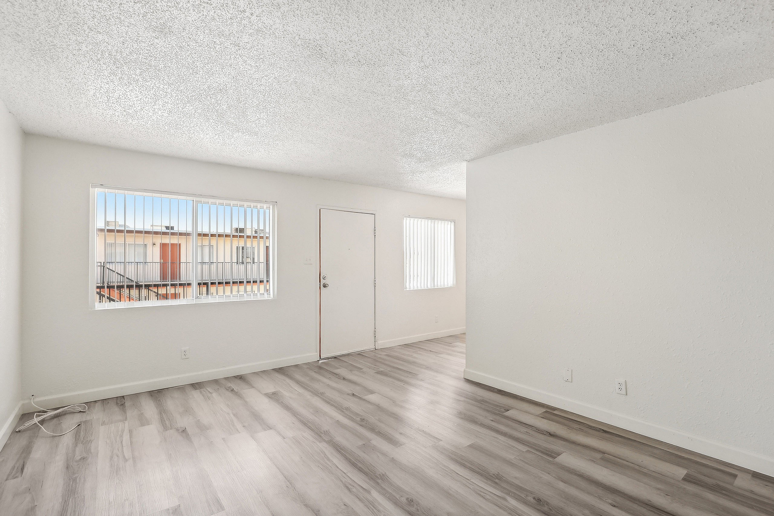 Bright and airy living space with modern hardwood flooring, enhanced by natural light through large windows.