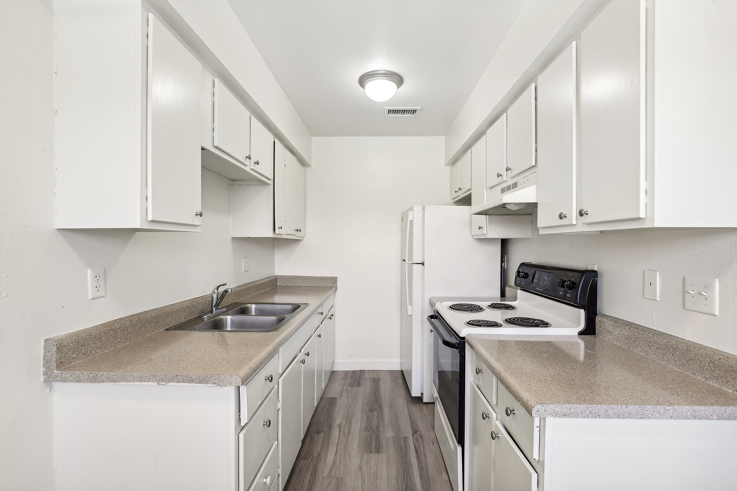 Bright, galley-style kitchen with modern white cabinets, sleek countertops, and a functional layout.