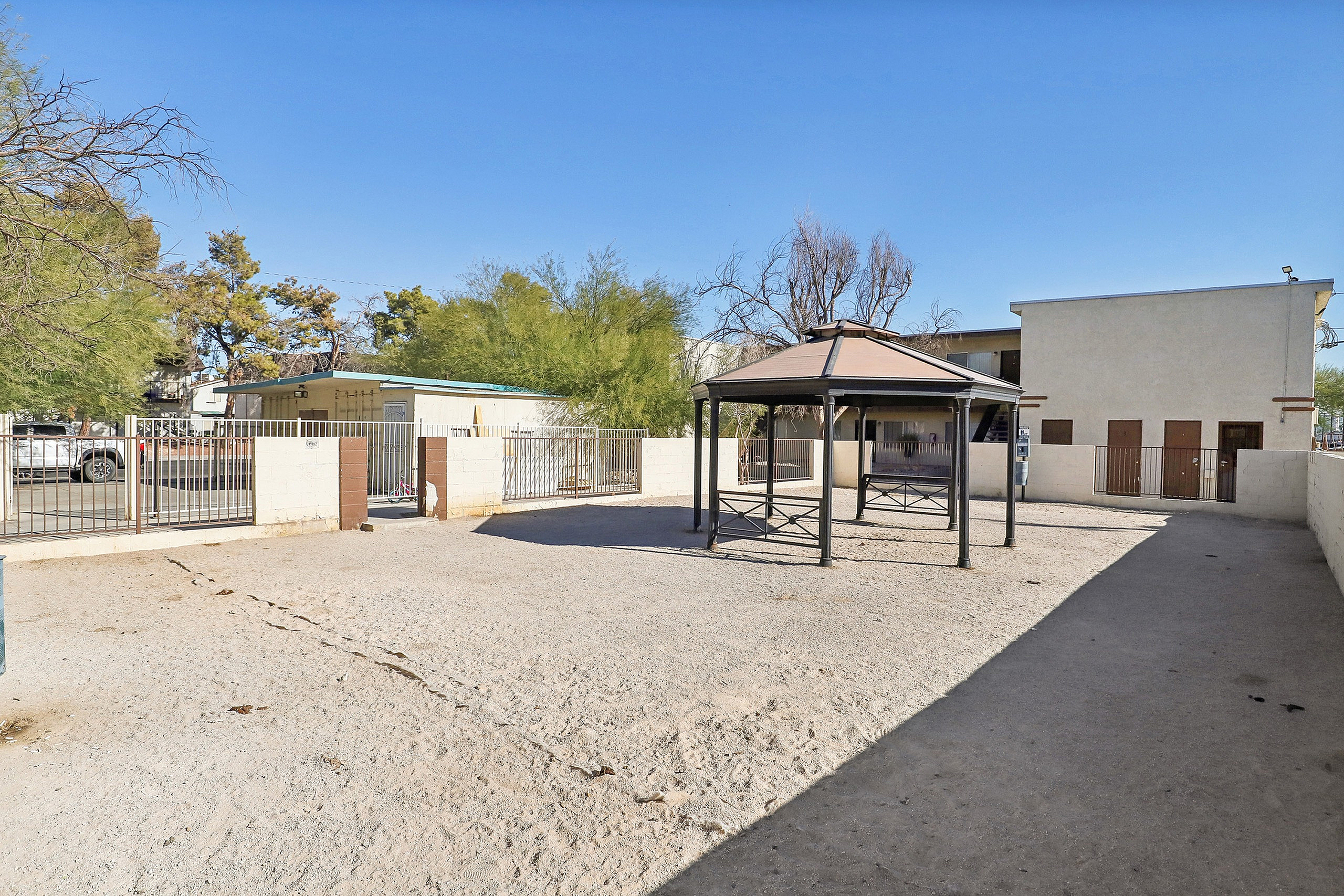 Inviting outdoor area with a stylish gazebo, perfect for relaxation, in a sunlit, spacious courtyard.