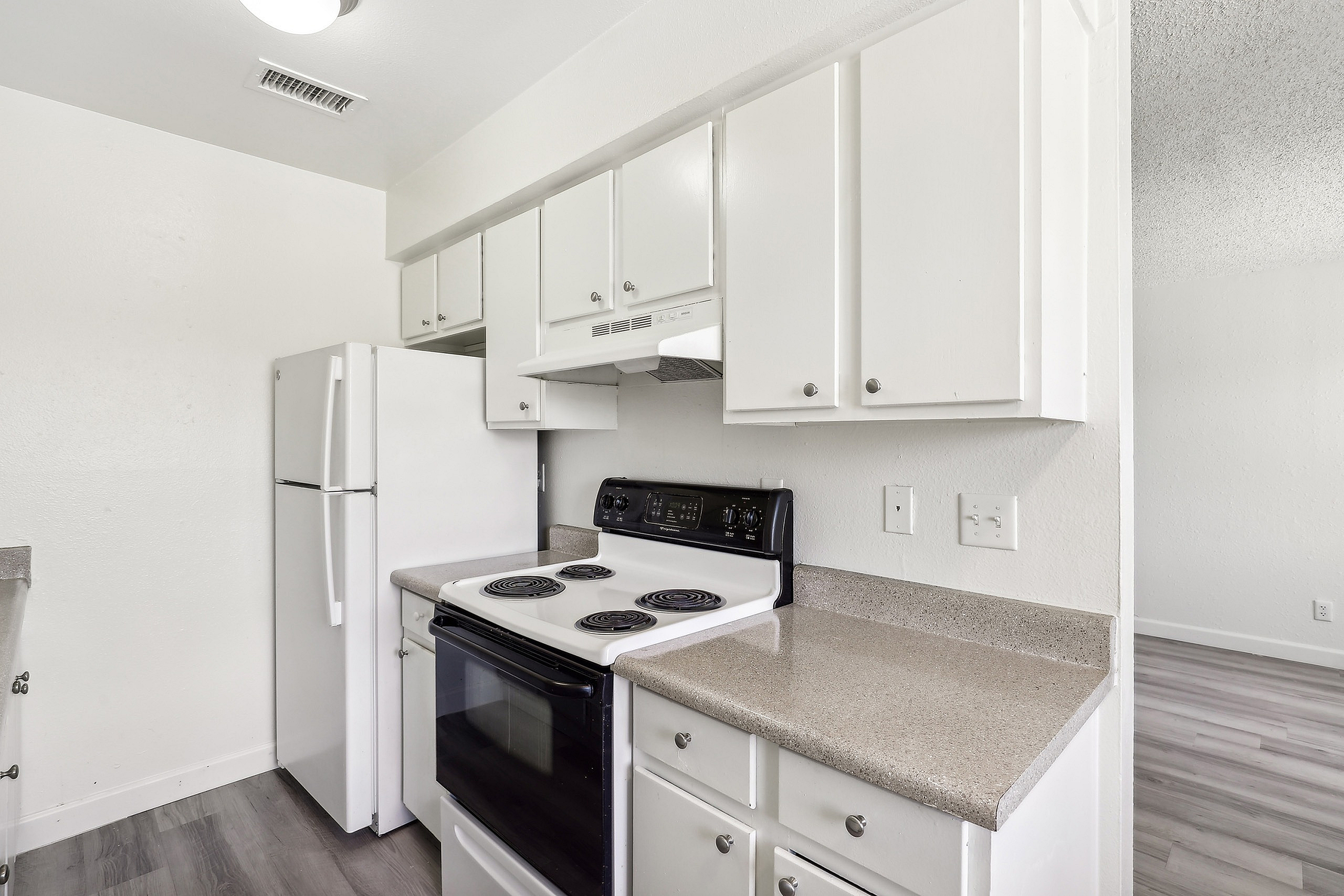 Modern kitchen with sleek white cabinetry, electric stove, and spacious countertops in a bright, inviting space.