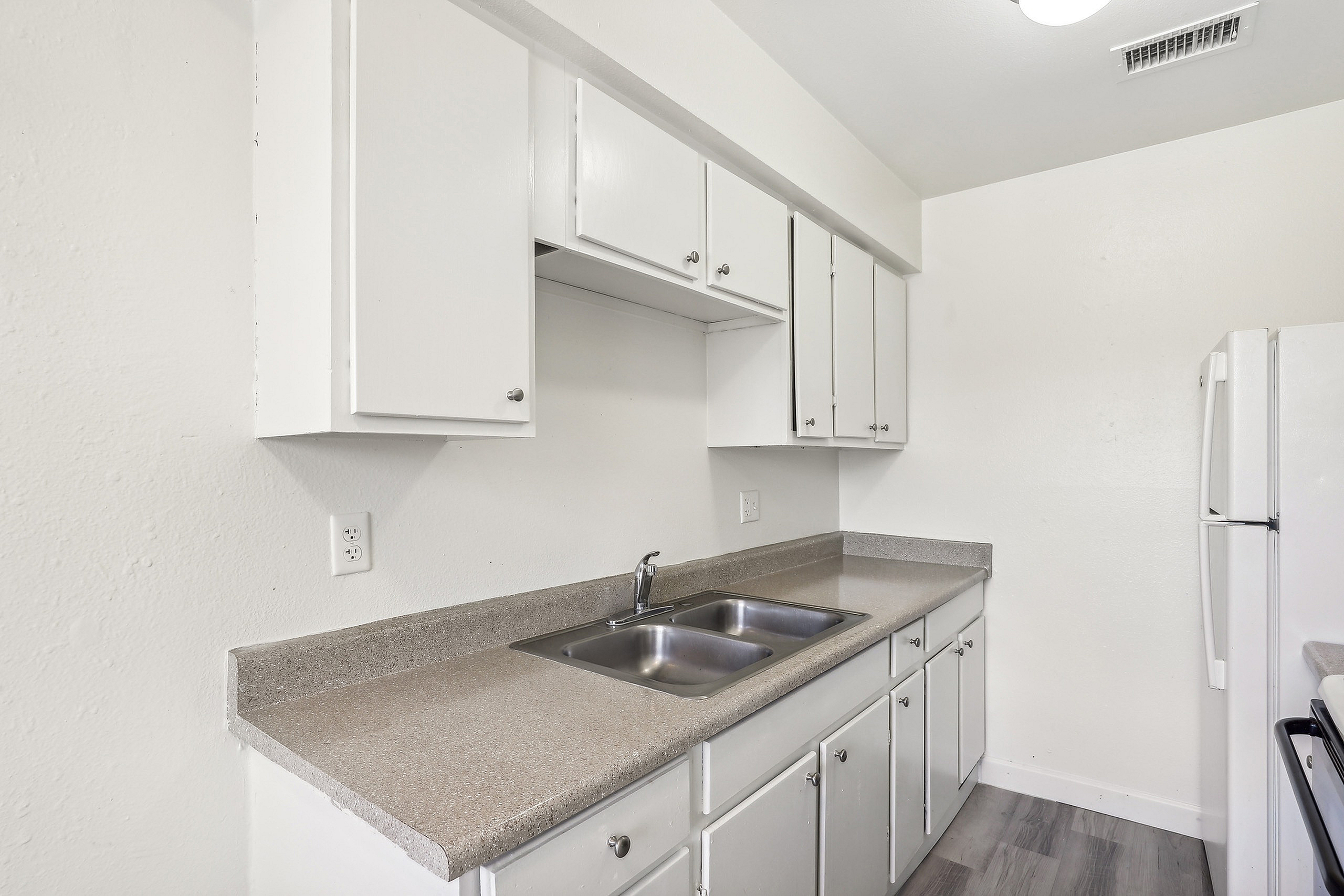 Modern kitchen with sleek white cabinets, spacious countertops, and a double sink.
