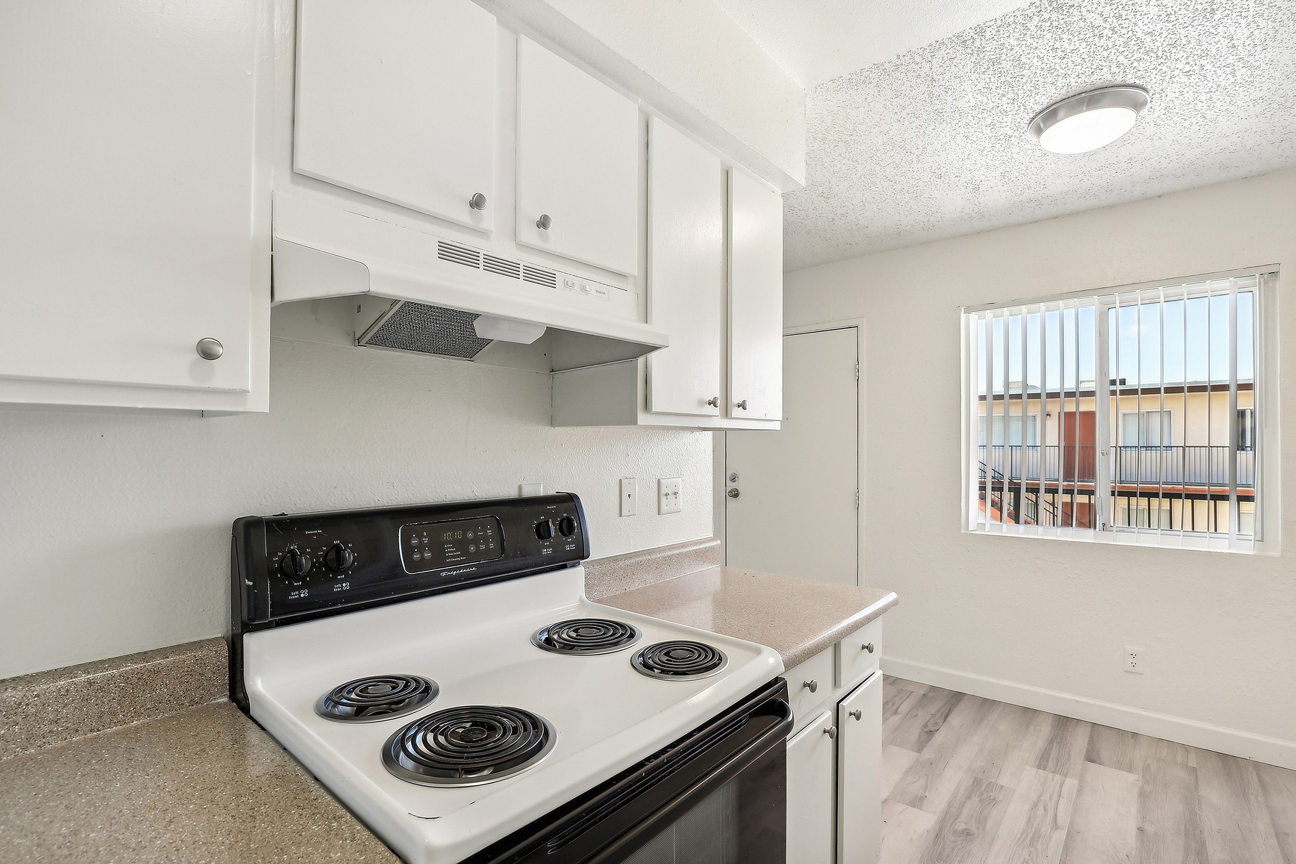 Bright kitchen with modern white cabinetry, electric stove, and a large window for natural light.