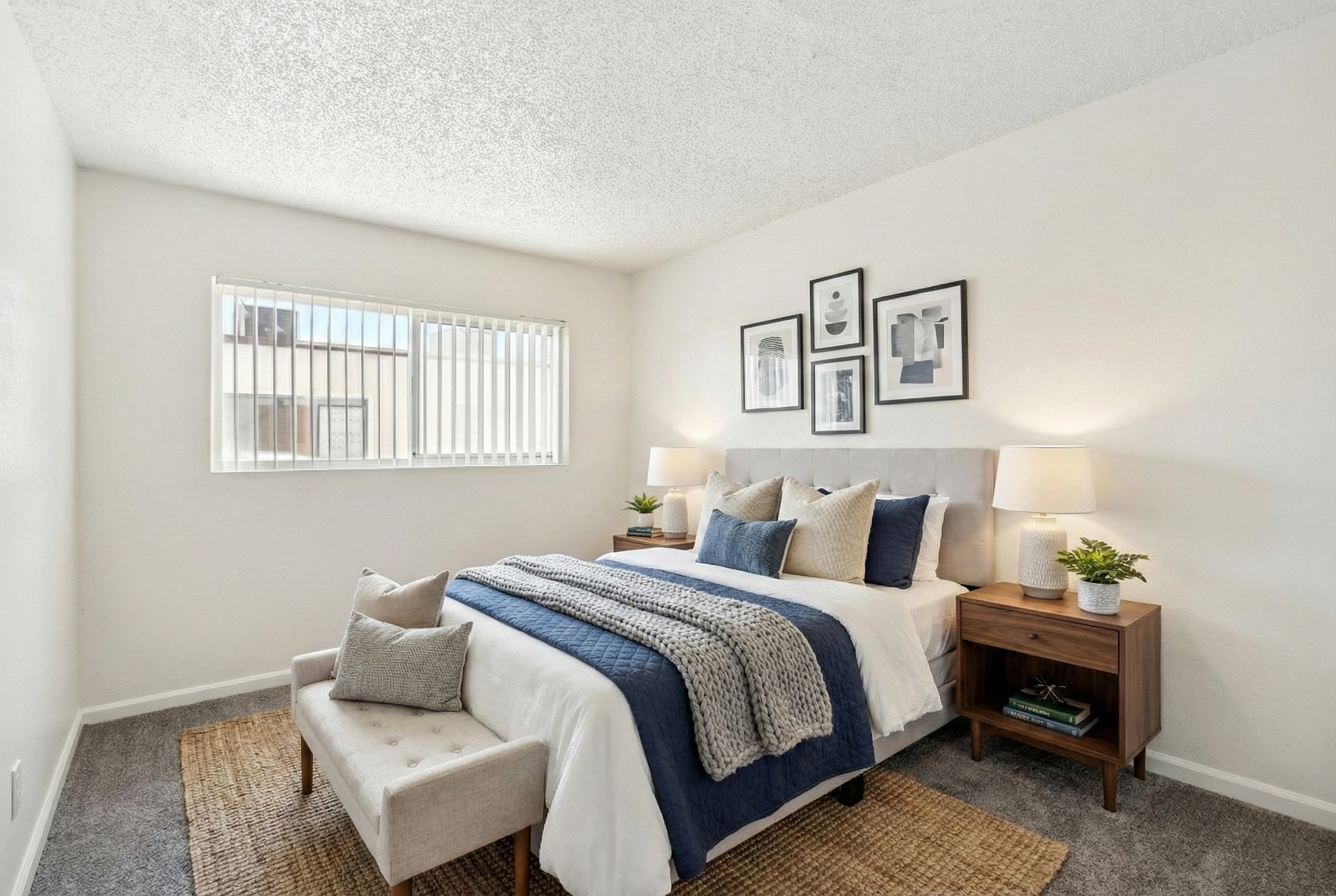Bright and modern bedroom featuring a cozy bed with stylish blue and gray bedding, elegant nightstands with chic lamps, and contemporary wall art creating a serene ambiance.