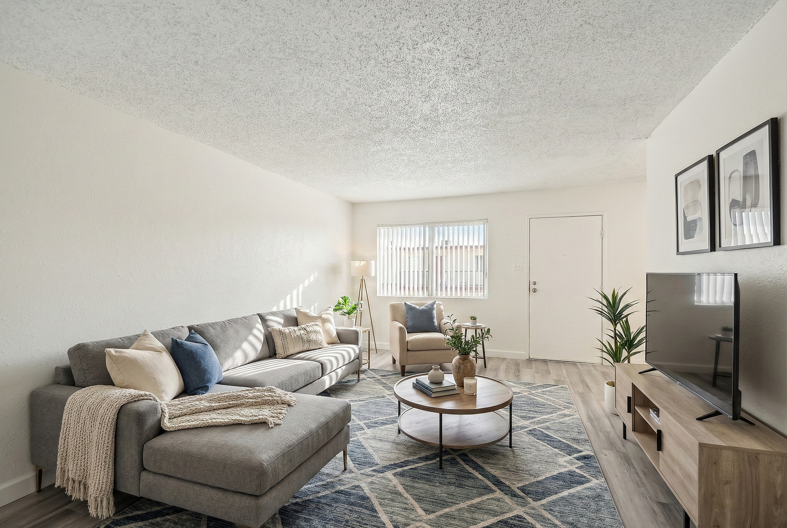 Bright and inviting living room with modern decor, featuring a cozy gray sectional, stylish coffee table, and sleek TV stand on elegant flooring.