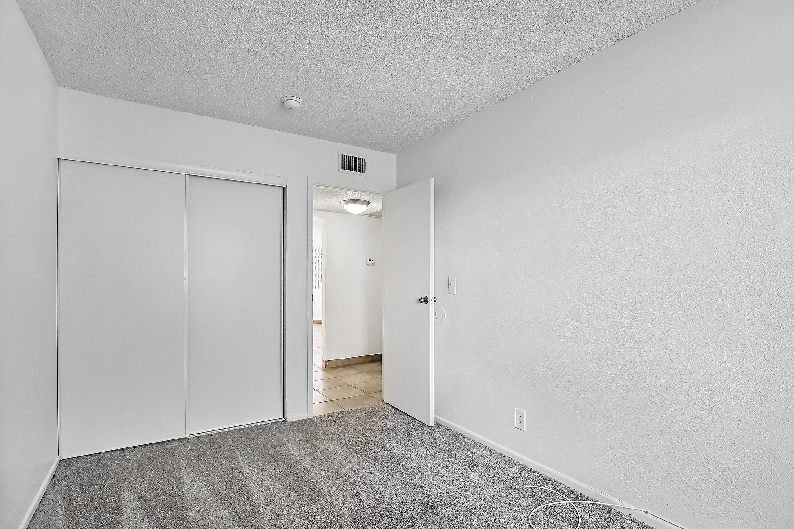 Bright, cozy bedroom with modern sliding closet doors and soft carpet flooring, offering a tranquil retreat.