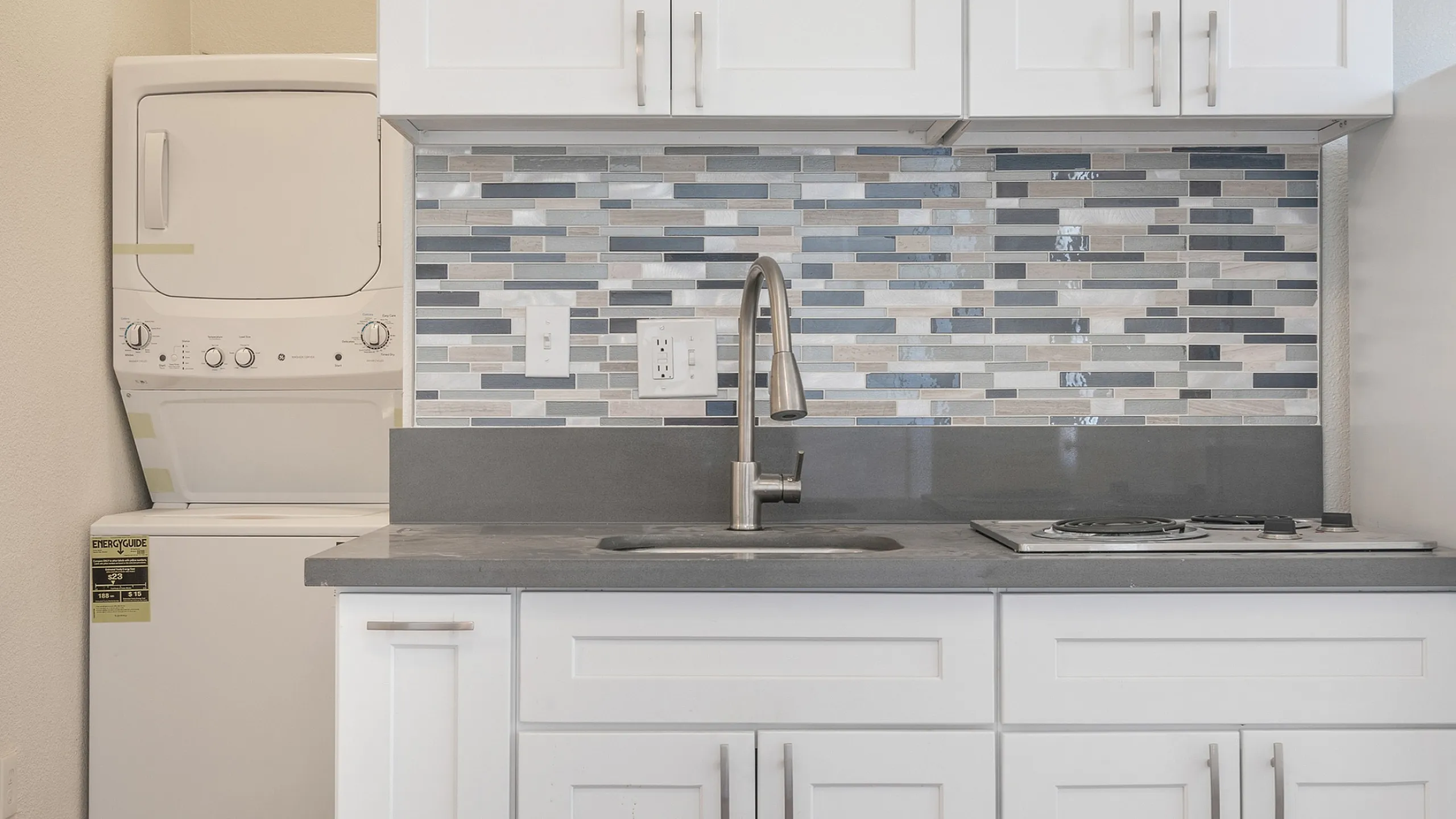 Modern kitchen with stylish backsplash, sleek countertops, and integrated washer-dryer for convenient living.