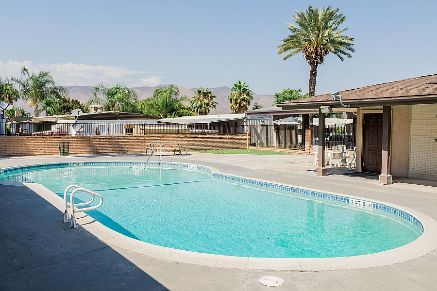 Inviting swimming pool area with palm trees and mountain views, perfect for relaxation.