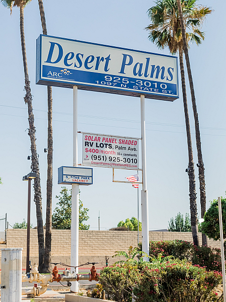 Inviting Desert Palms sign showcasing vibrant community with solar panel shaded RV lots and lush greenery.