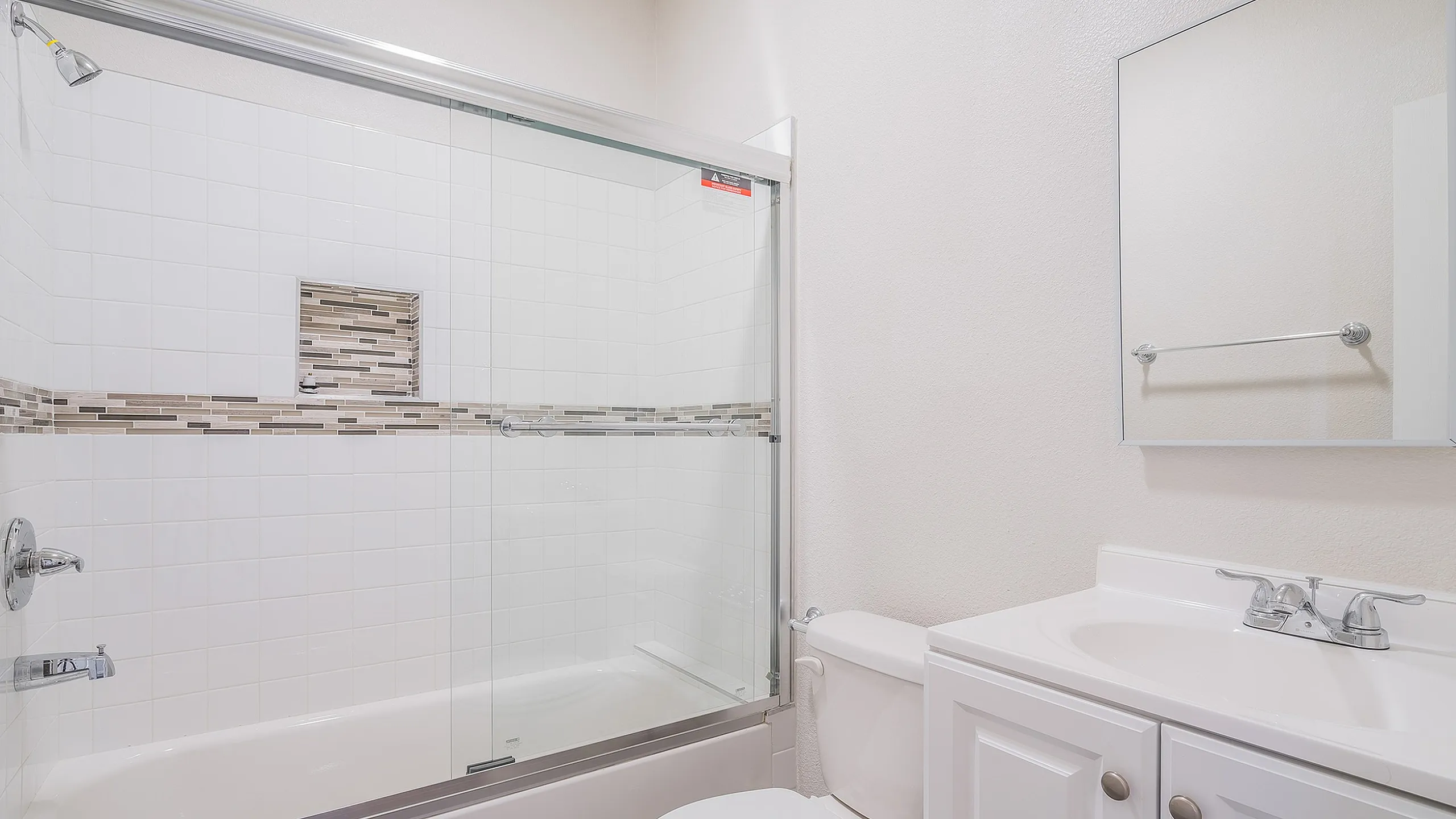 Elegant bathroom with modern fixtures, featuring a glass-enclosed shower and sleek vanity with ample storage.