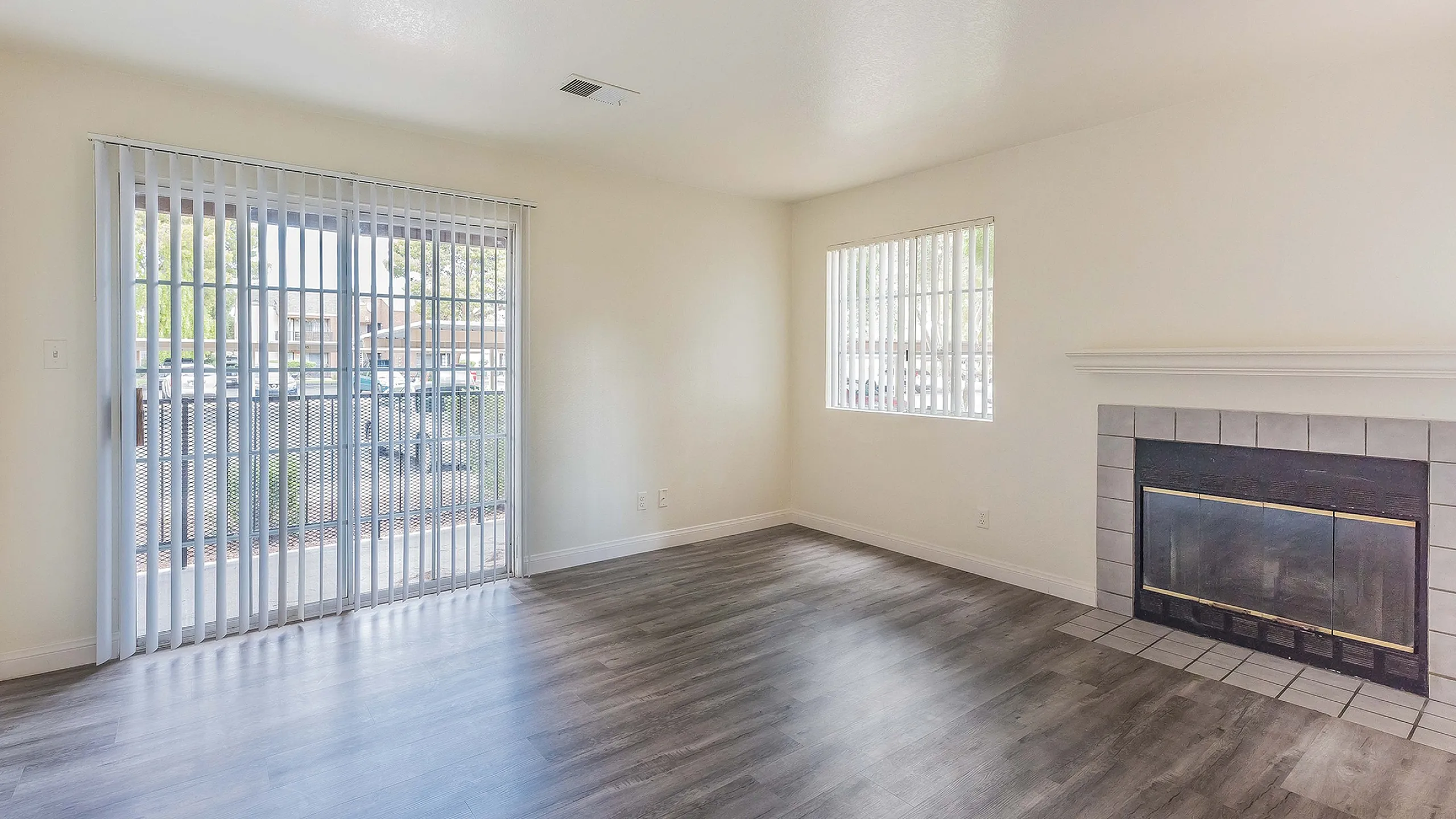 Bright and inviting living room featuring elegant hardwood floors, large windows with ample natural light, and a cozy fireplace, offering a perfect blend of style and comfort.