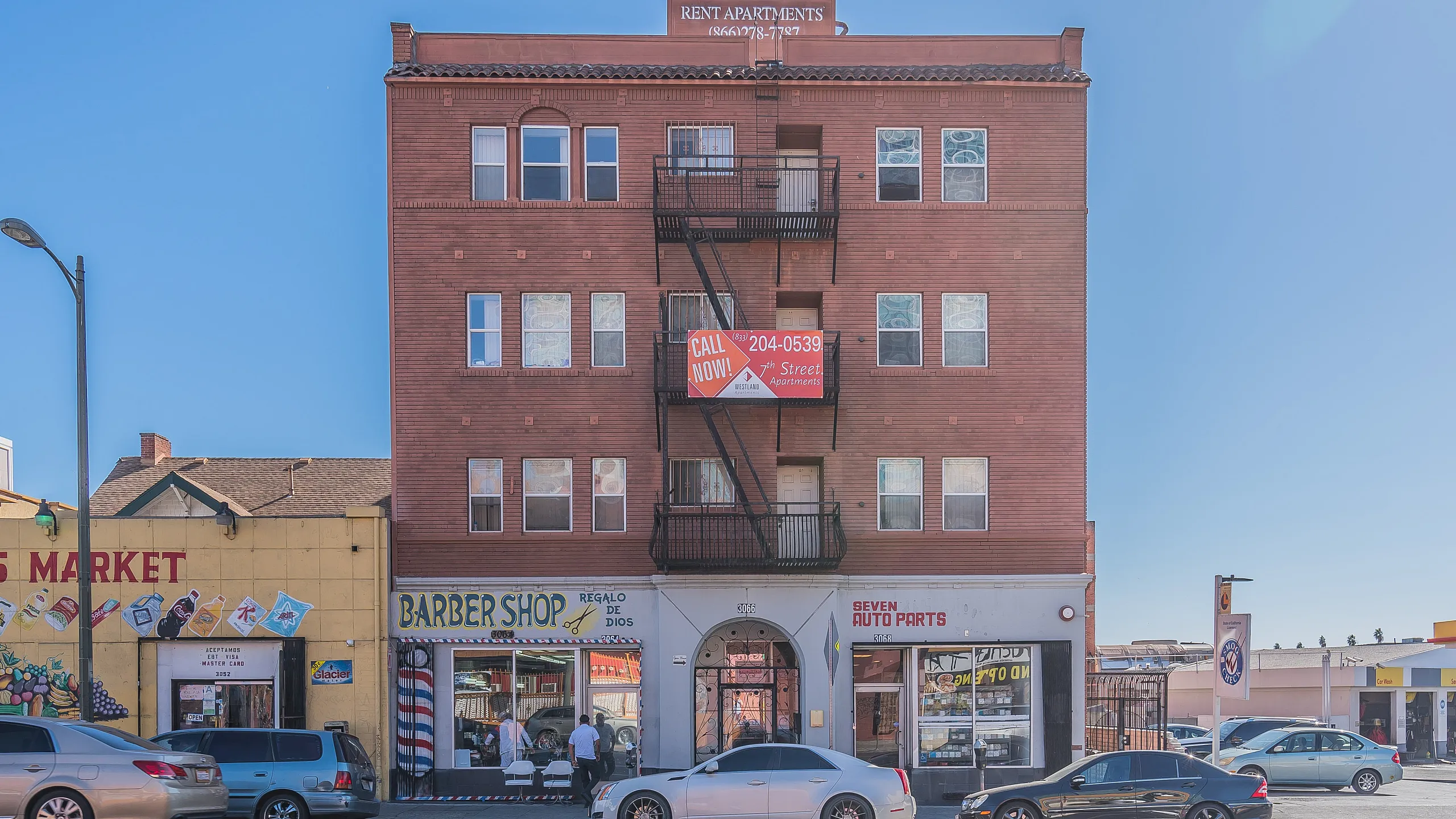 Charming urban apartment building with classic red brick facade, nestled above vibrant local shops in a lively neighborhood.
