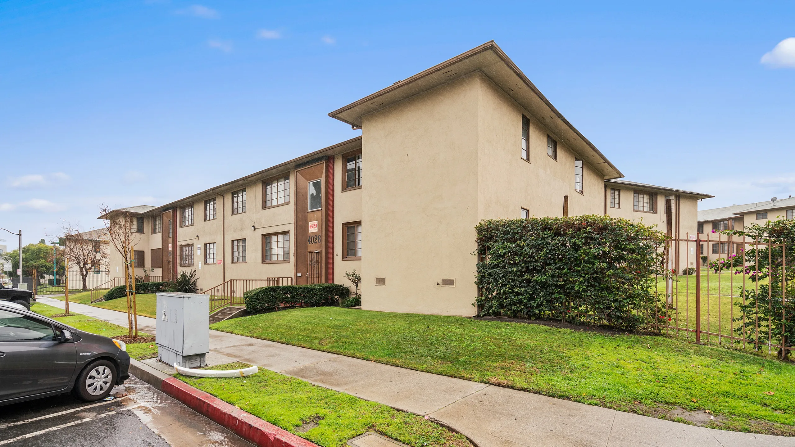Charming two-story apartment building with a well-maintained lawn, offering a serene suburban vibe.