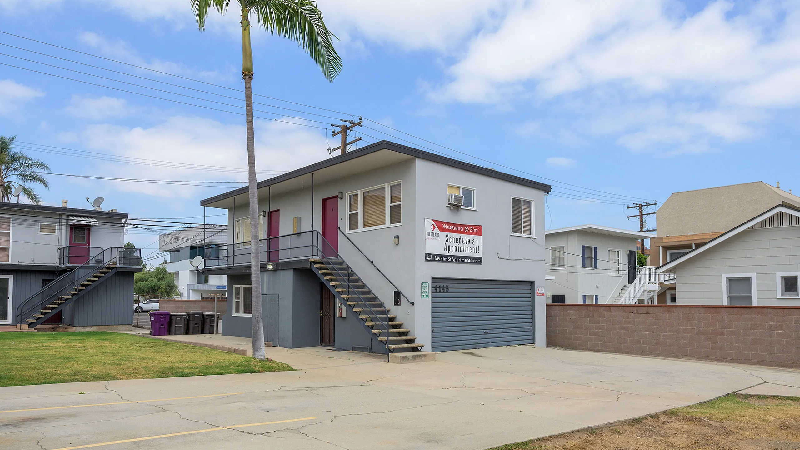 Inviting apartment building with modern exterior, convenient stair access, and lush palm trees, ideal for comfortable living.