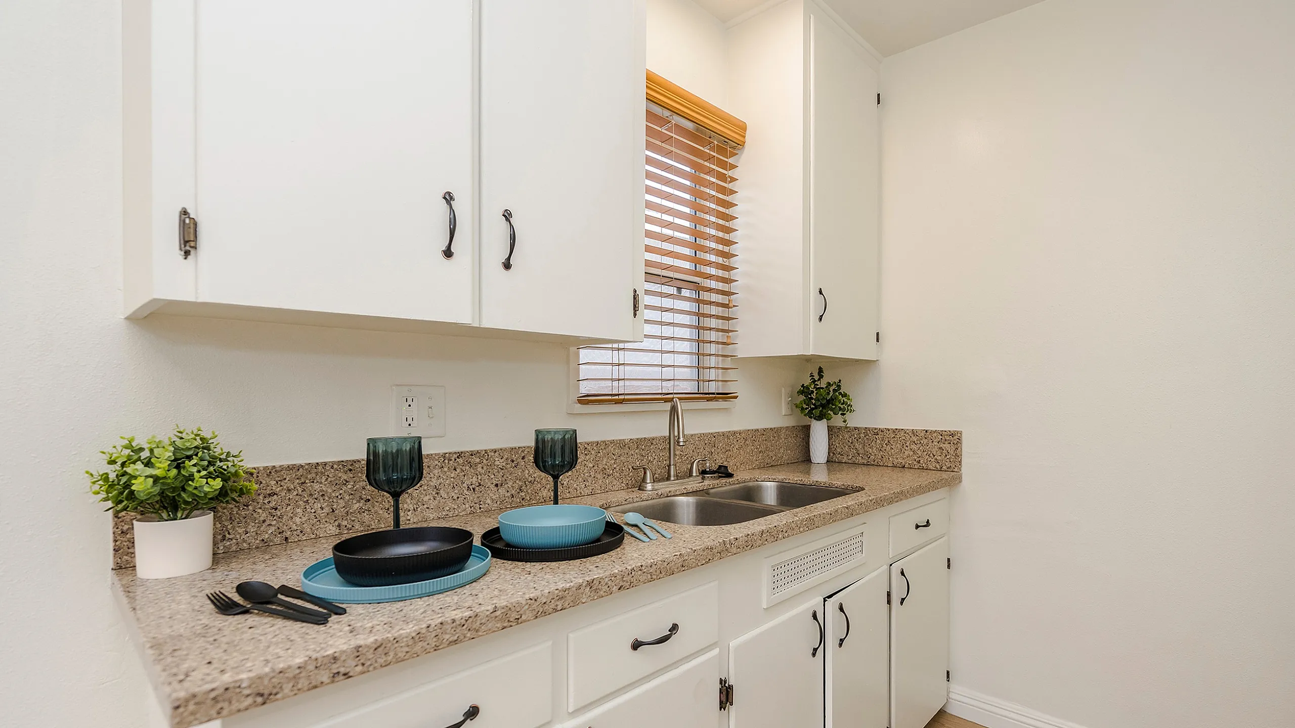 Charming kitchen with white cabinets, sleek granite countertops, and modern fixtures, perfect for culinary creativity.