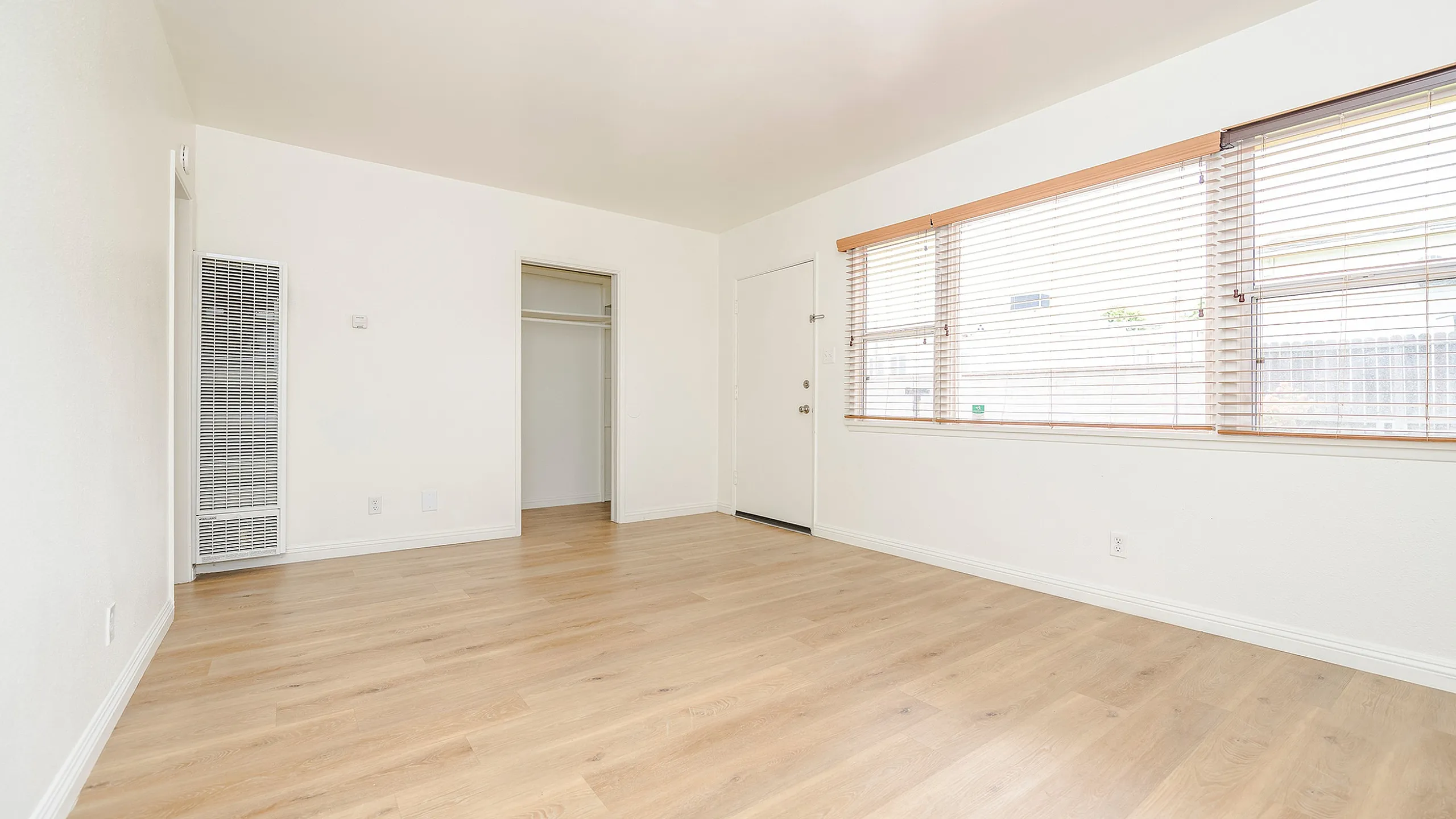 Spacious, bright room featuring modern wood flooring and large windows, perfect for a cozy living space.