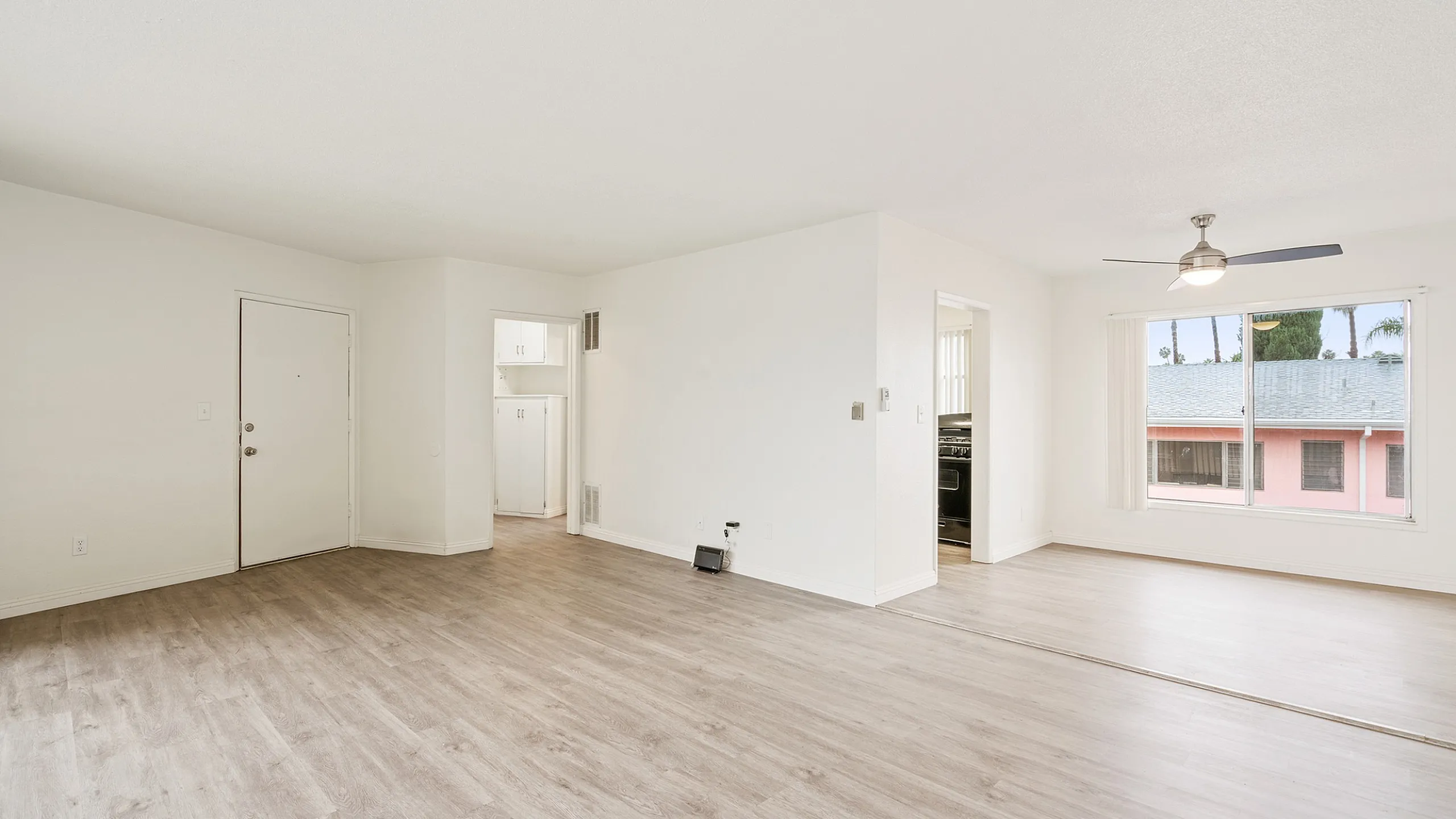 Bright and spacious open-plan living area with large windows, modern light fixtures, and elegant wood flooring.