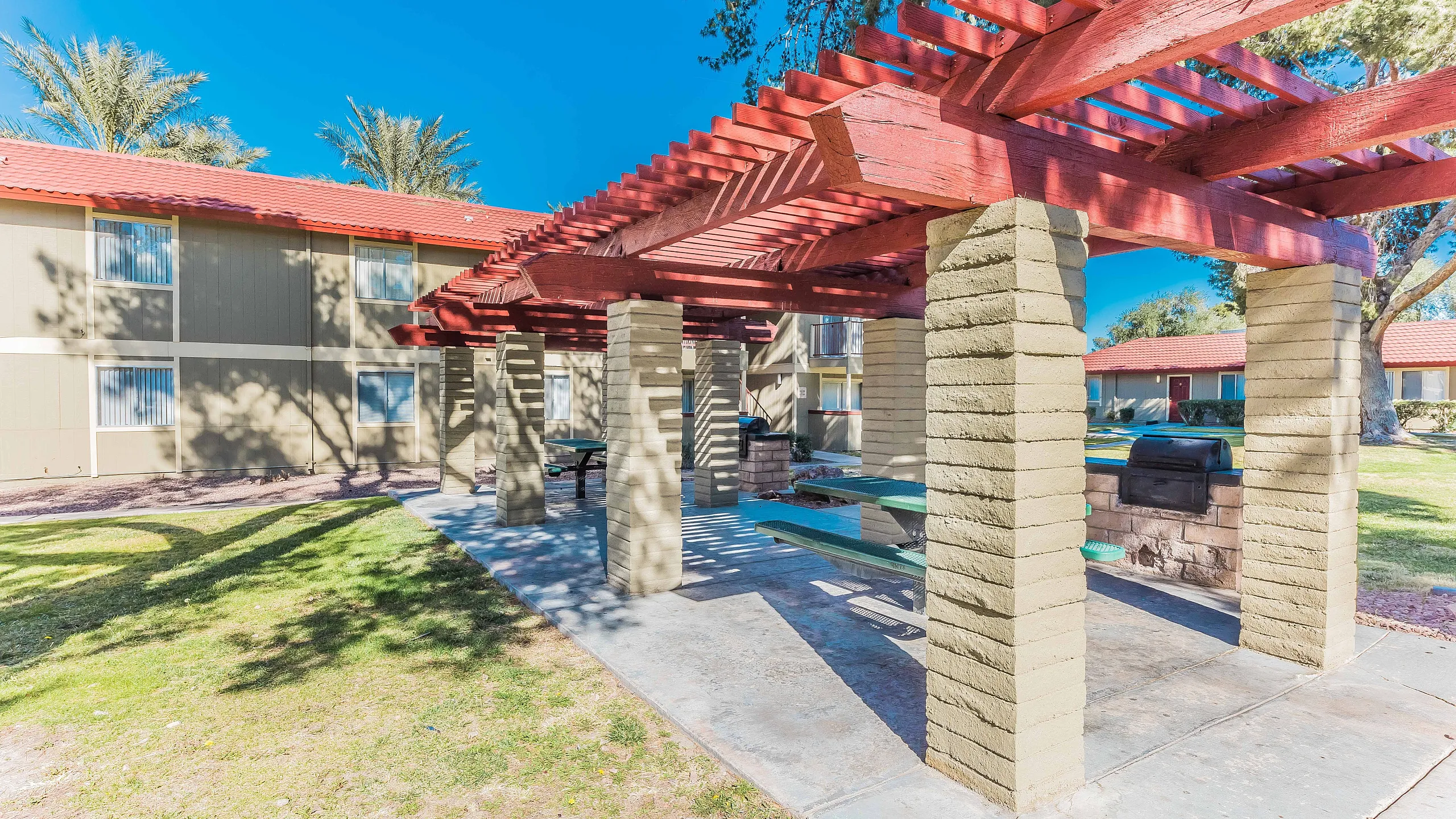Charming outdoor space with rustic pergola, perfect for gatherings, set against a backdrop of lush greenery and blue skies.