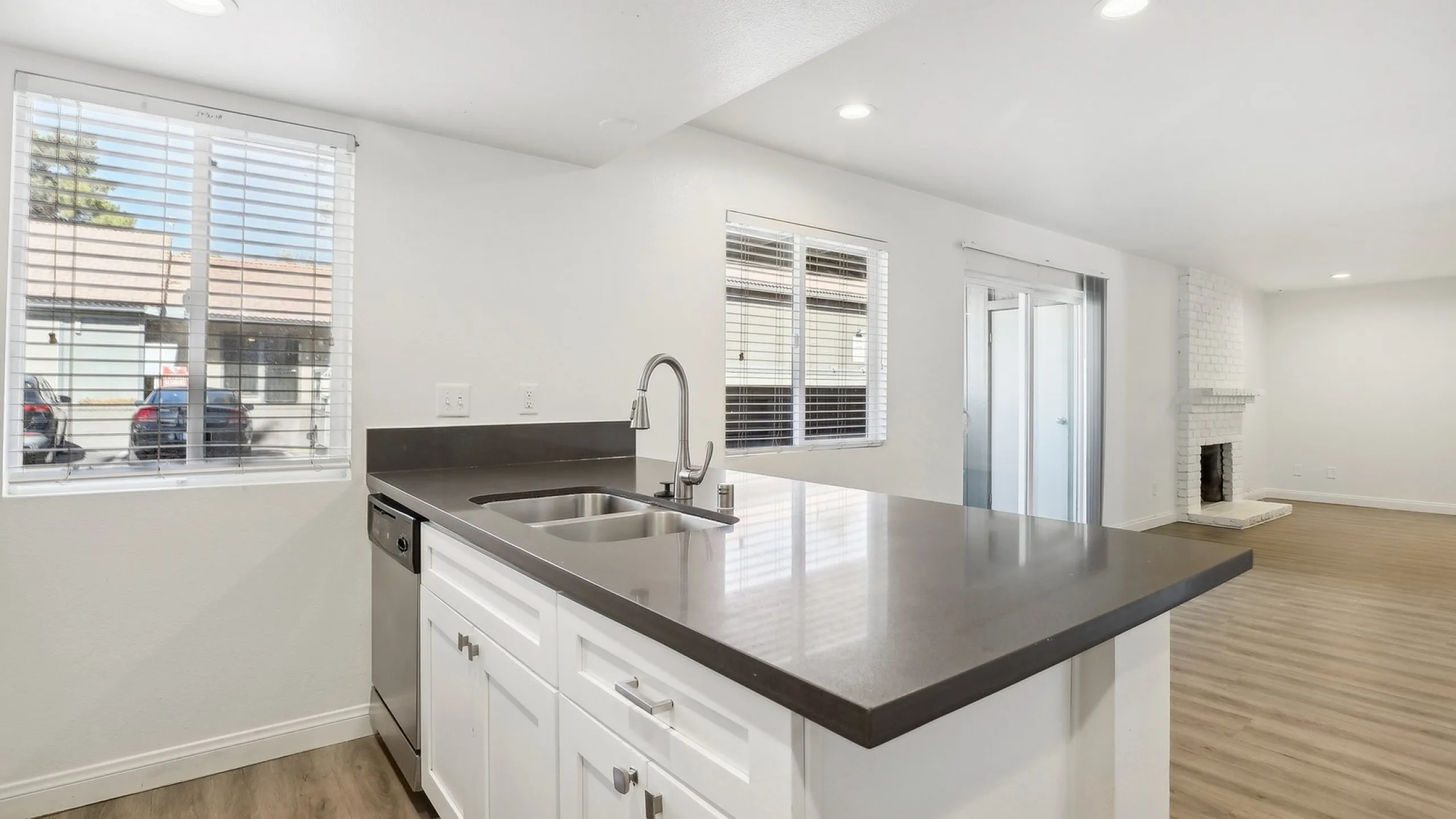 Modern open-concept kitchen with sleek countertops, white cabinetry, and elegant living area featuring large windows and a cozy fireplace.