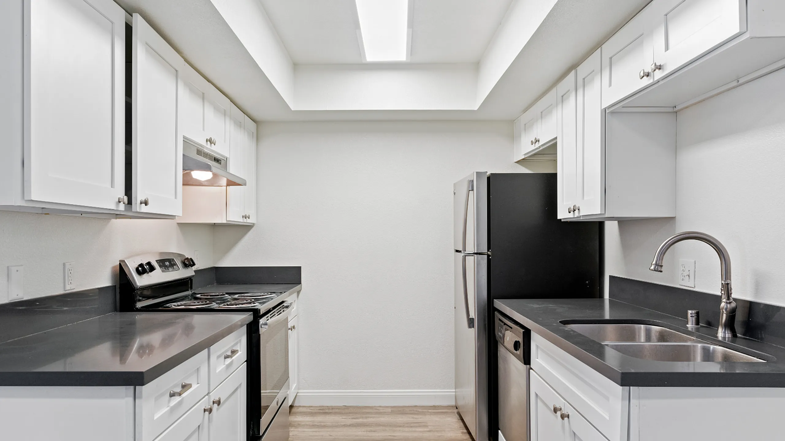 Modern kitchen with sleek countertops and stainless steel appliances, featuring ample white cabinetry for stylish storage.