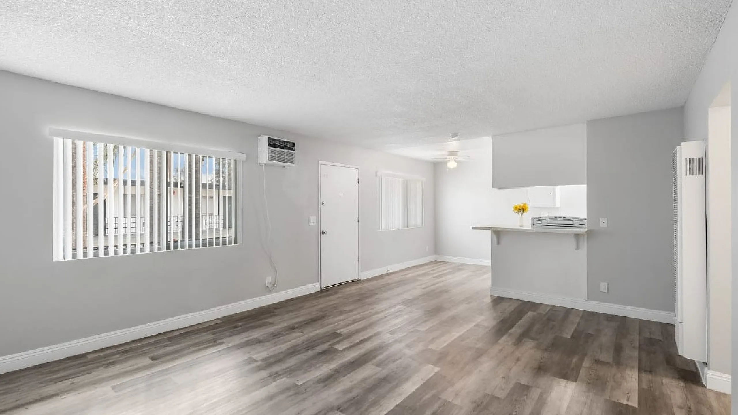 Bright living area with chic wooden flooring, an elegant open layout, and ample natural light pouring through large windows.