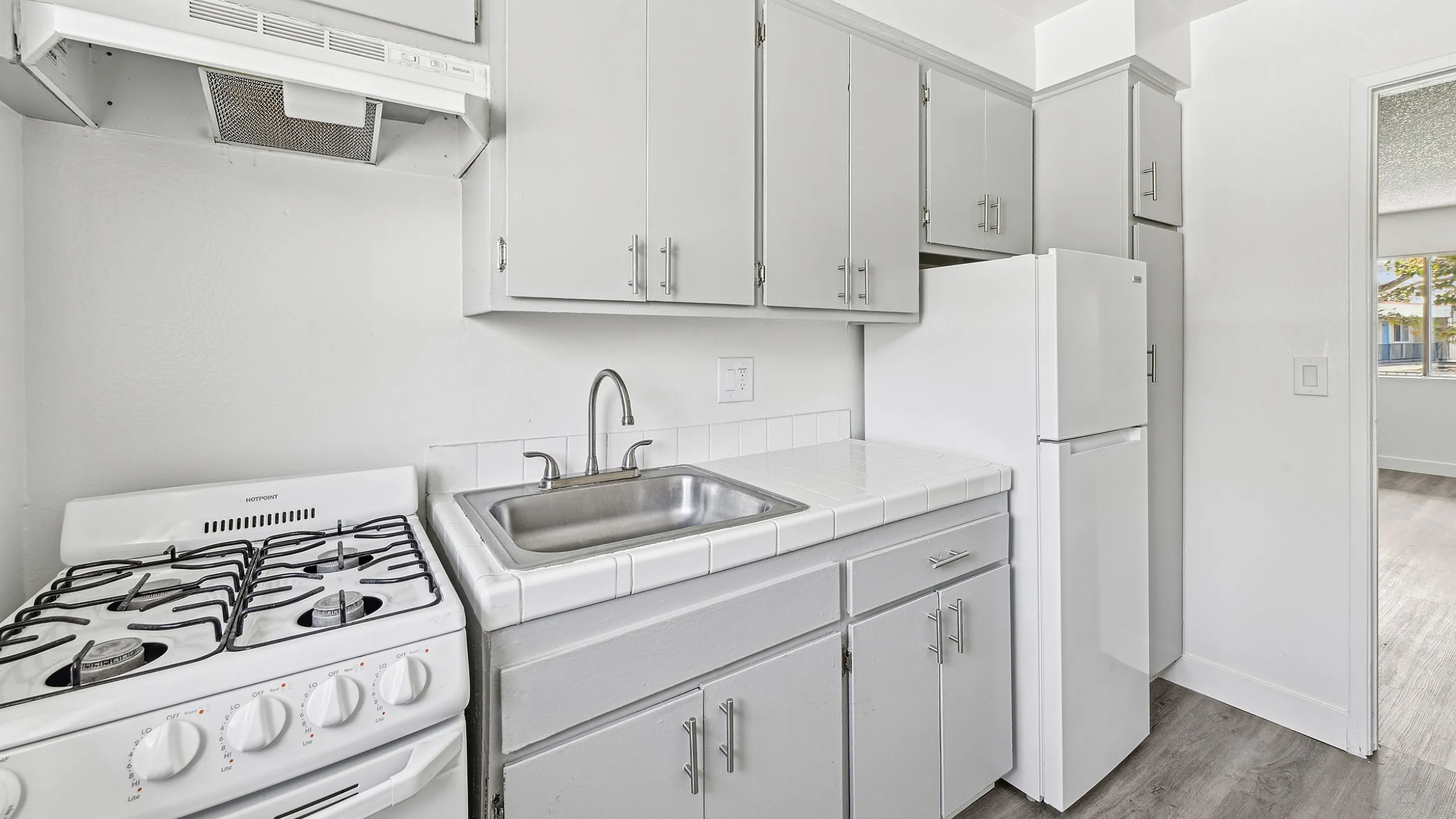 Charming kitchen with modern gray cabinets, sleek white countertops, and a classic gas stove.