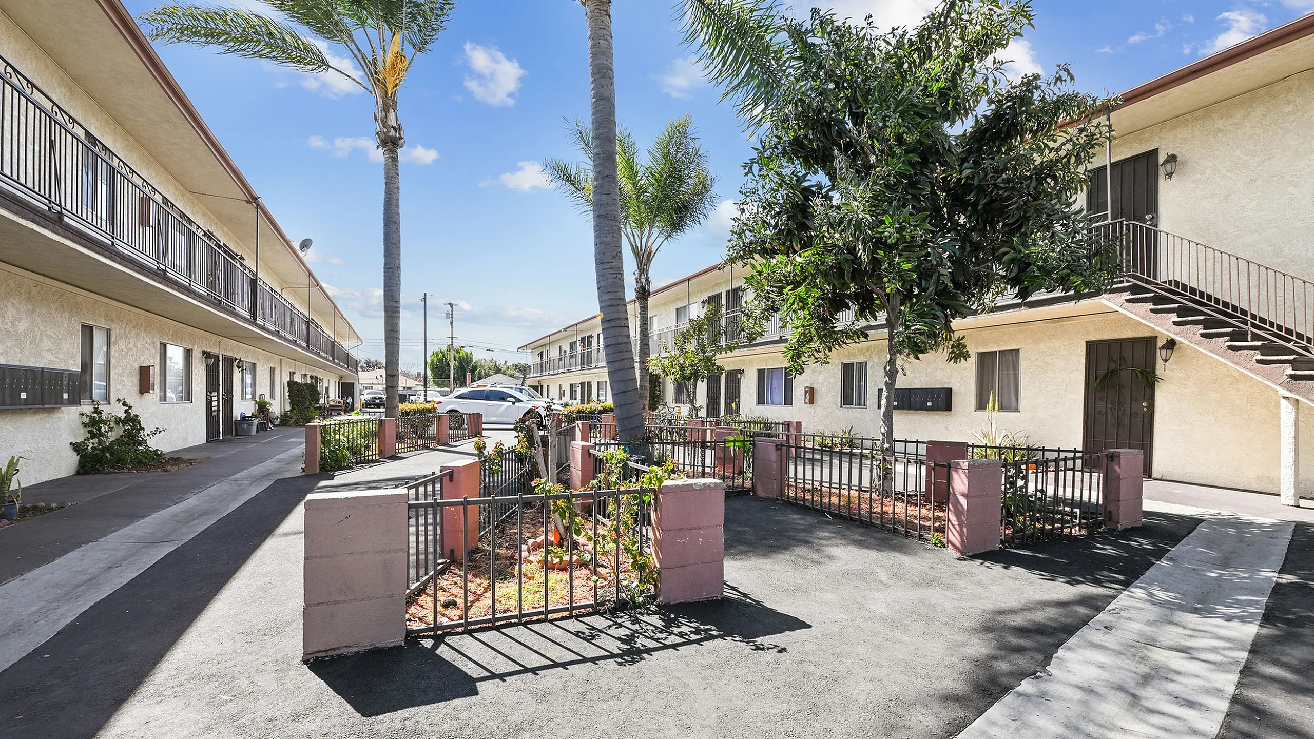 Charming apartment complex with lush greenery, palm trees, and inviting walkways, perfect for sunny living.