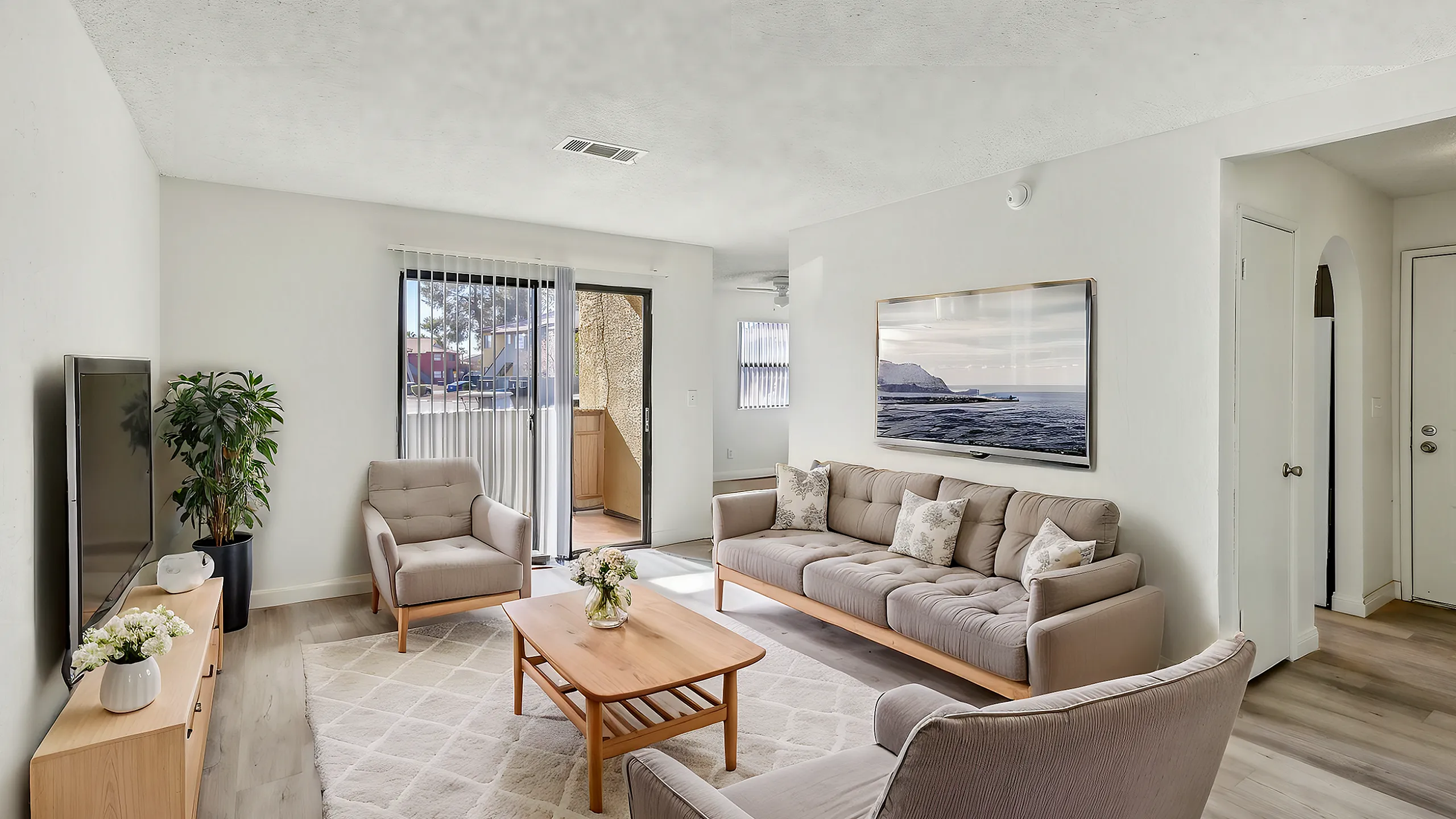 Inviting living room with plush seating, modern decor, and ample natural light from large glass door opening to balcony.