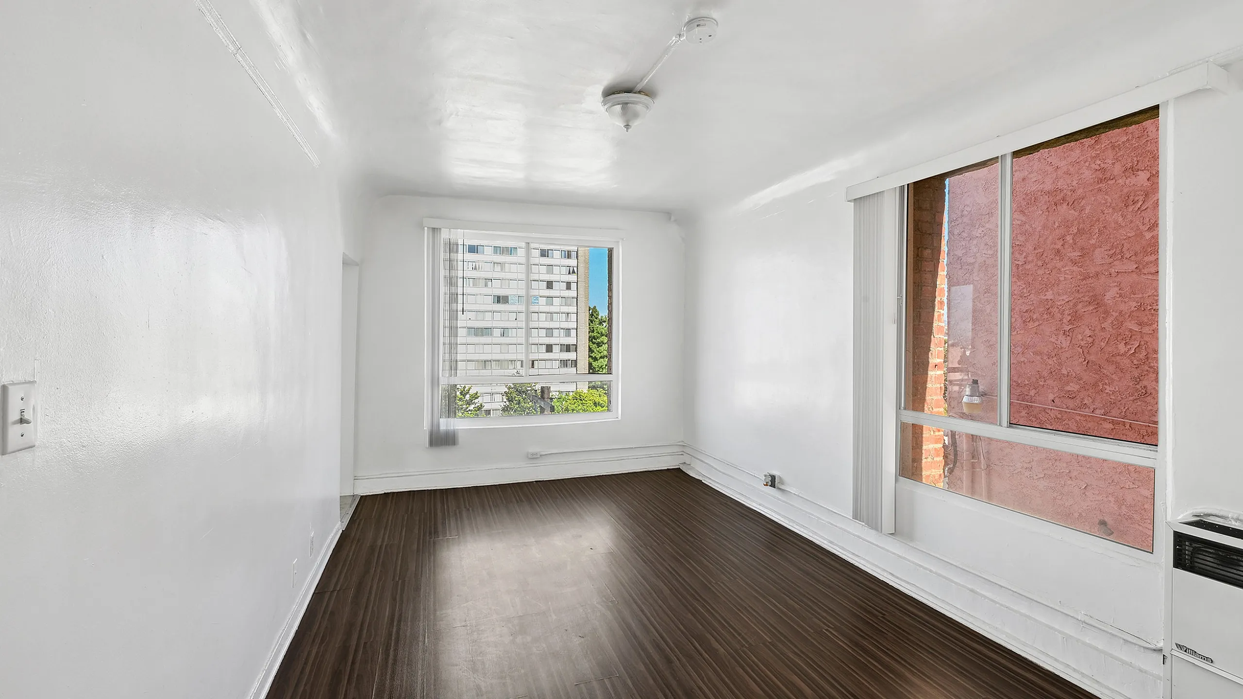 Bright and airy room with elegant wood flooring, large windows, and fresh white walls, creating a perfect blank canvas for personalized style.